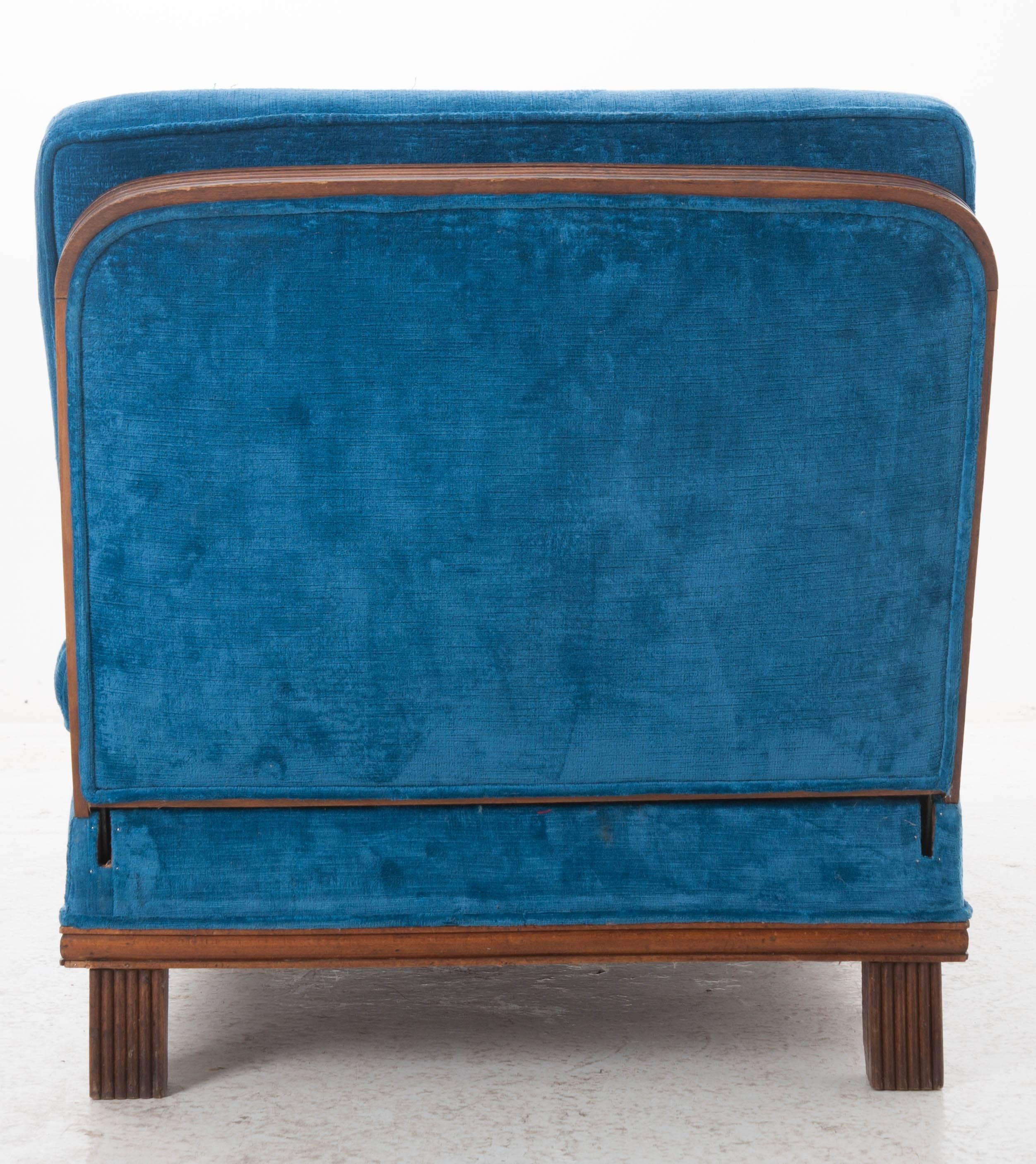 A fabulous walnut Art Deco period daybed that has been upholstered in a striking blue velvet from 1930s, France. This upholstered piece has sides that can be arranged into three configurations, gradually transitioning from settee to bed. This