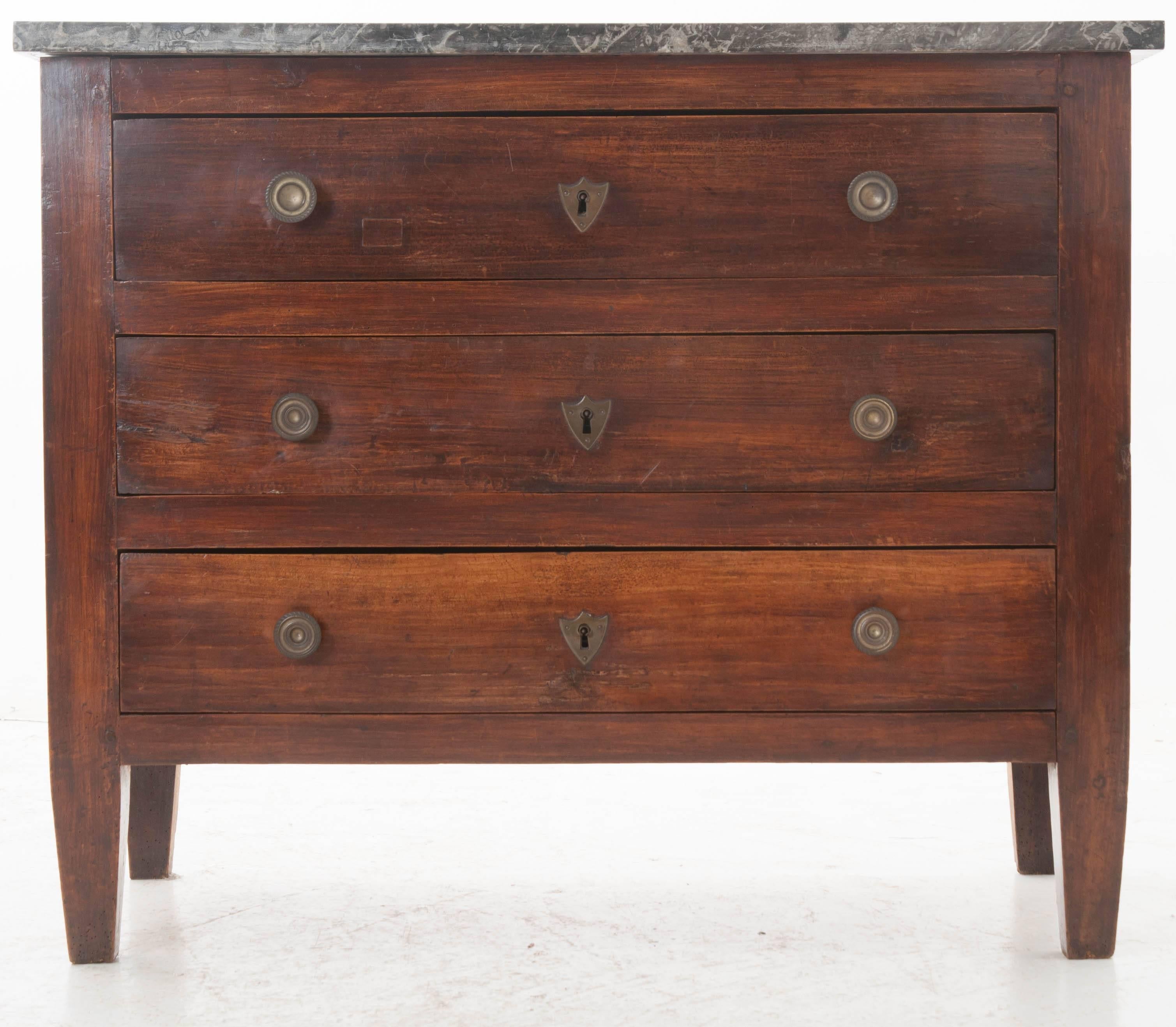 Combining elements of Directoire and Empire styles, this great little transitional three-drawer commode has a style that is all its own. The gray marble top is in good antique condition with vibrant white veins running throughout. Empirically