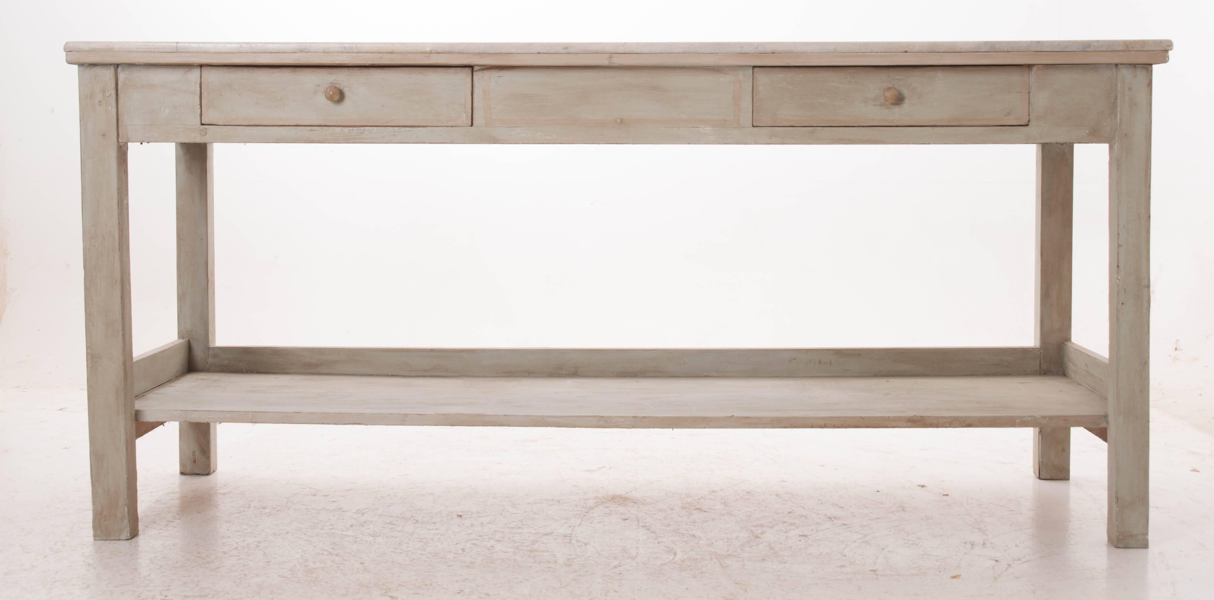 A stunning piece of antique white marble was affixed to a more recently painted base to create this perfectly suited baker's work table. The apron houses two drawers for out of sight storage, while an undertier shelf below allows for additional