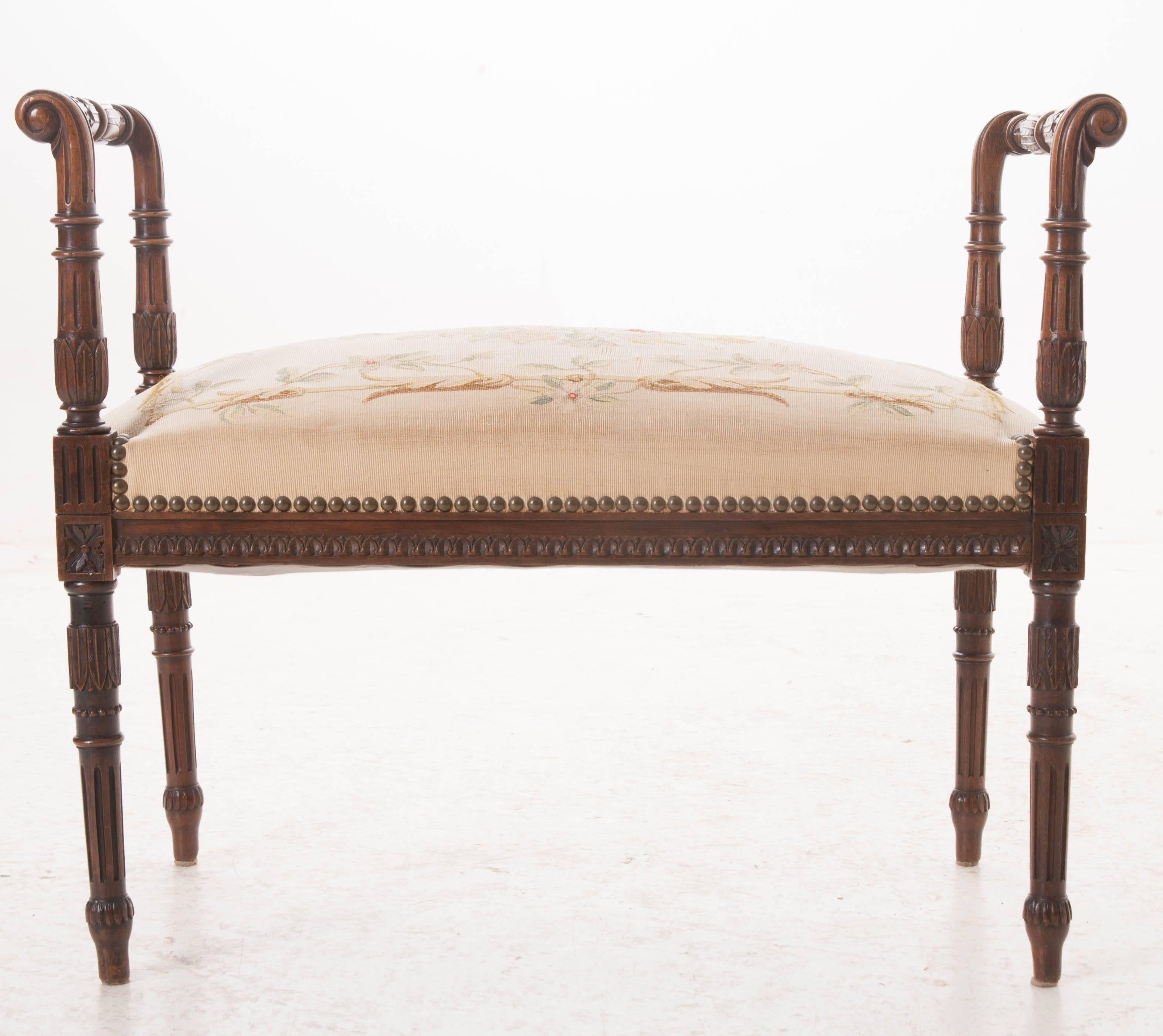 An outstanding Louis XVI period mahogany window seat with tapestry upholstery from early 19th century, France. The refined frame boasts exceptionally well carved details with foliate, fluted, and lamb's tongue motifs just to name a few. The tapestry