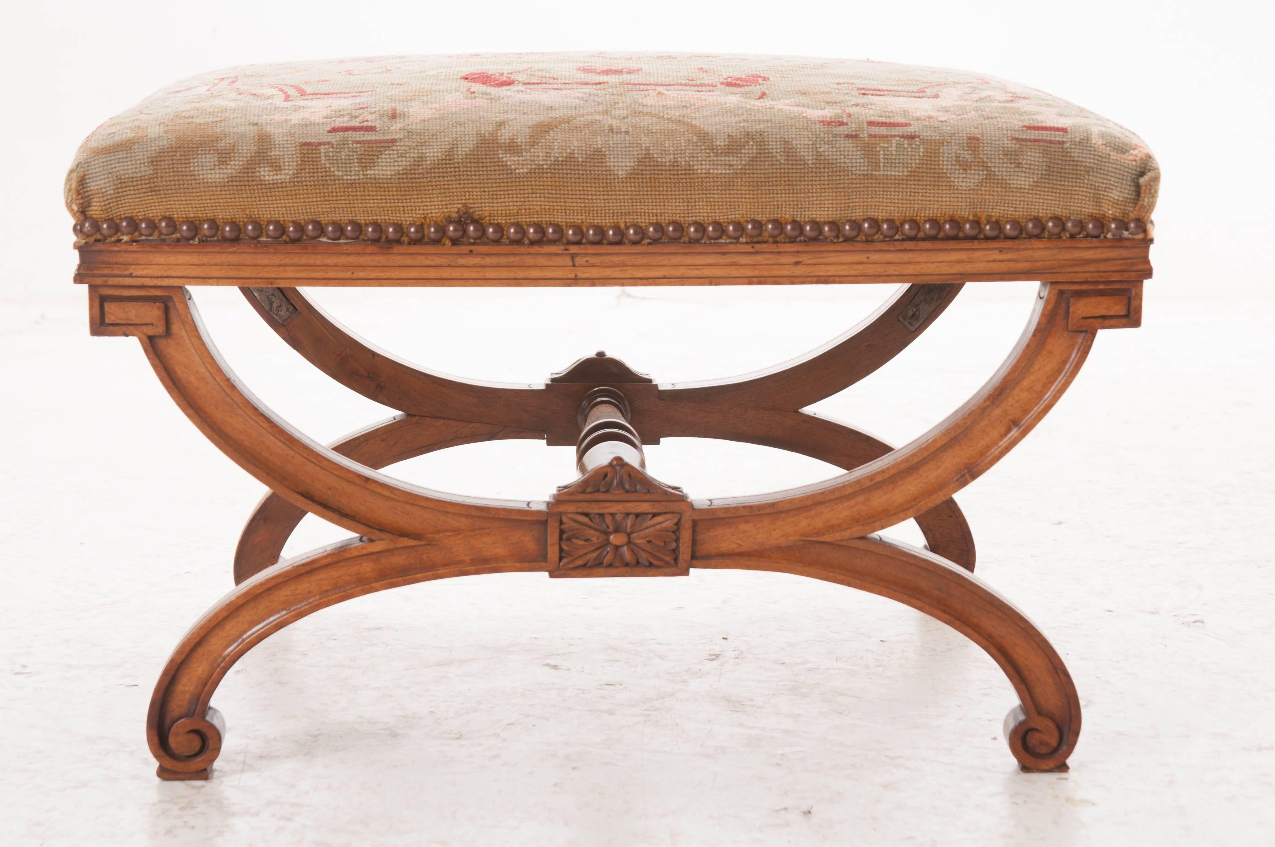 A sensational 19th century French carved walnut stool with a gorgeous needlepoint tapestry seat. Incorporating elements of Louis XVI, the shaped X-frame base is solid and stabile. The base is reinforced with an expertly turned walnut stretcher. The