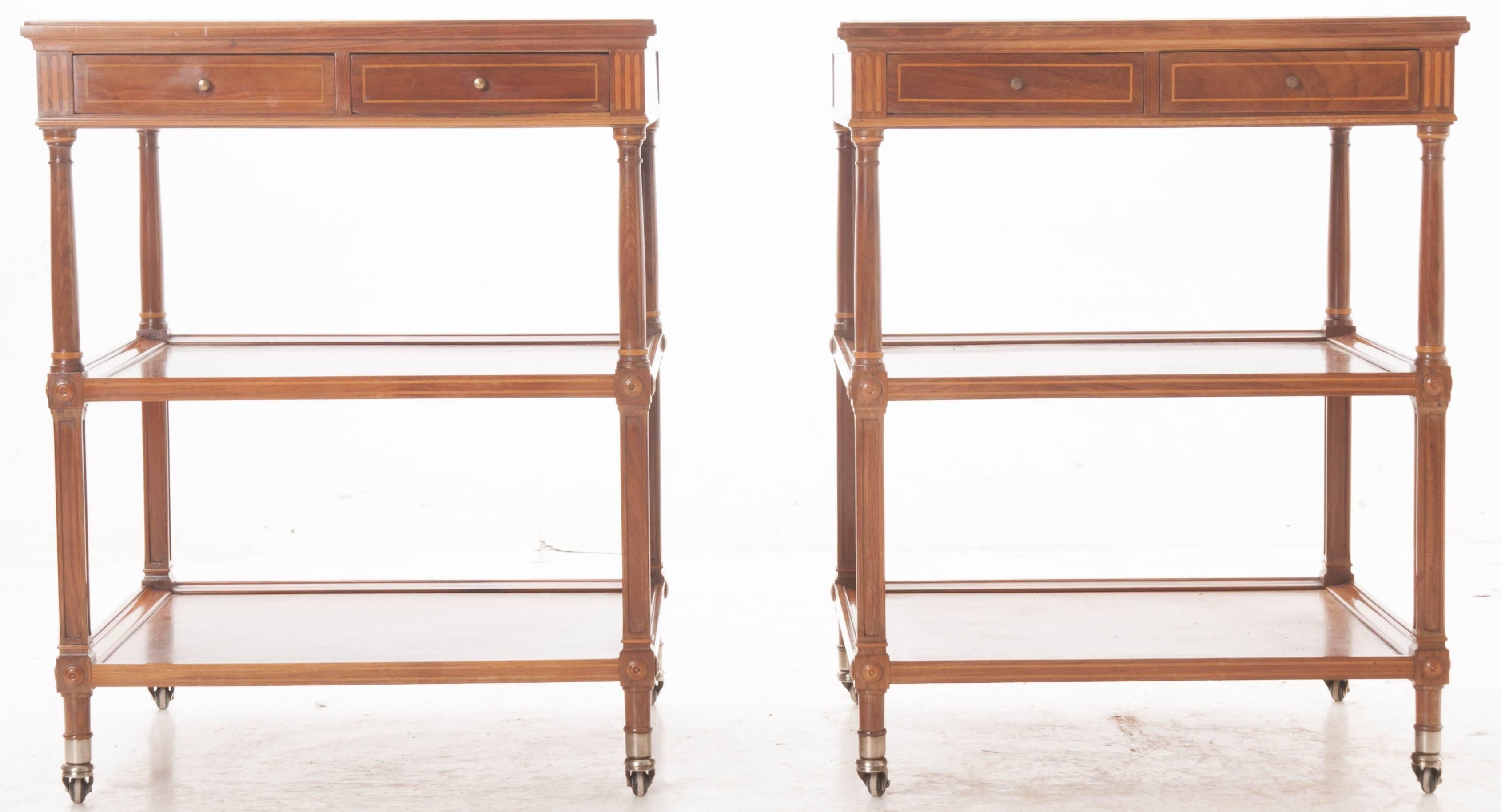 A darling pair of marble-top mahogany bedside tables from early 20th century France. Each table has a beautiful white marble-top that is flecked with gray veins and both tops are in excellent antique condition. The aprons each contain two small