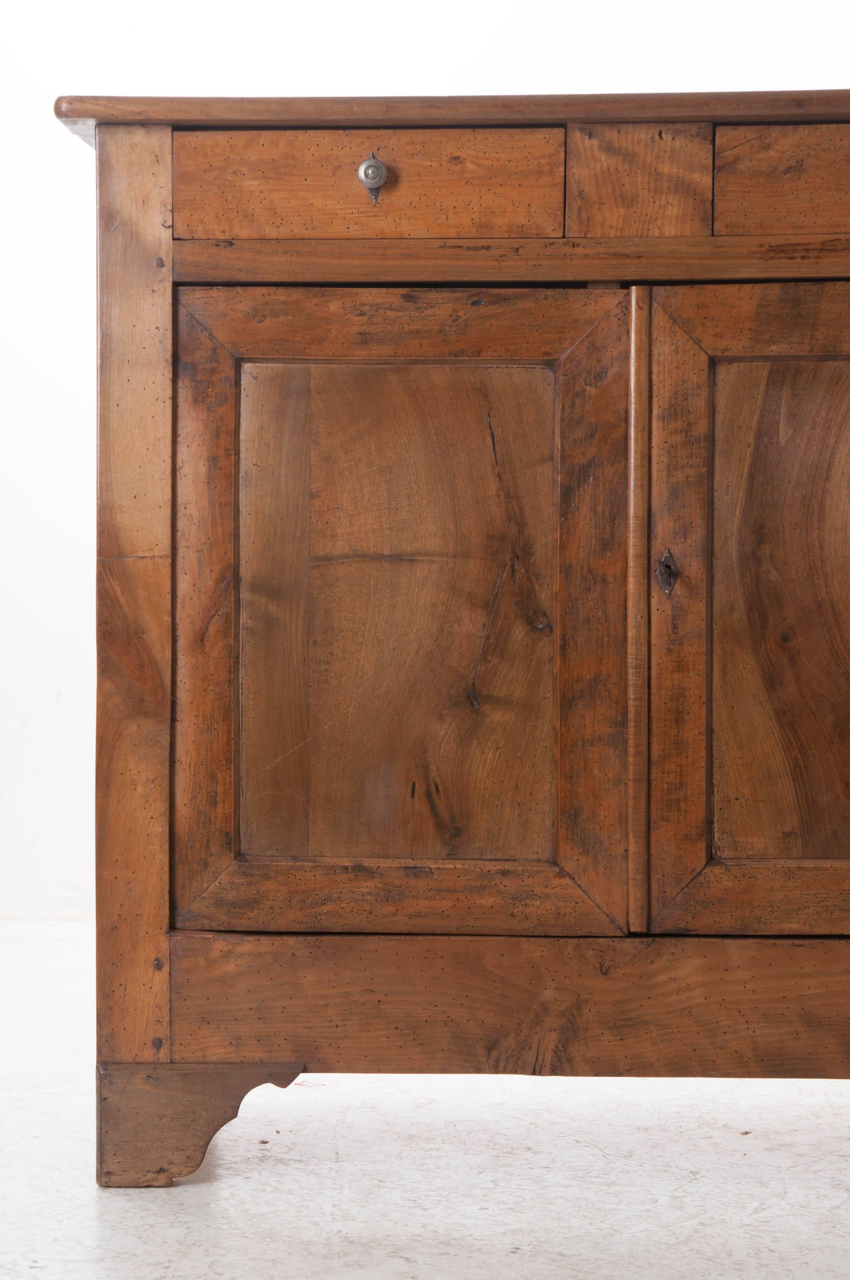 A delightful, tall French Louis Philippe buffet composed of solid walnut, pine and oak. This lightly toned buffet is designed with clean, straight lines, making this, and all Louis Philippe style pieces, extraordinarily versatile. The buffet has two