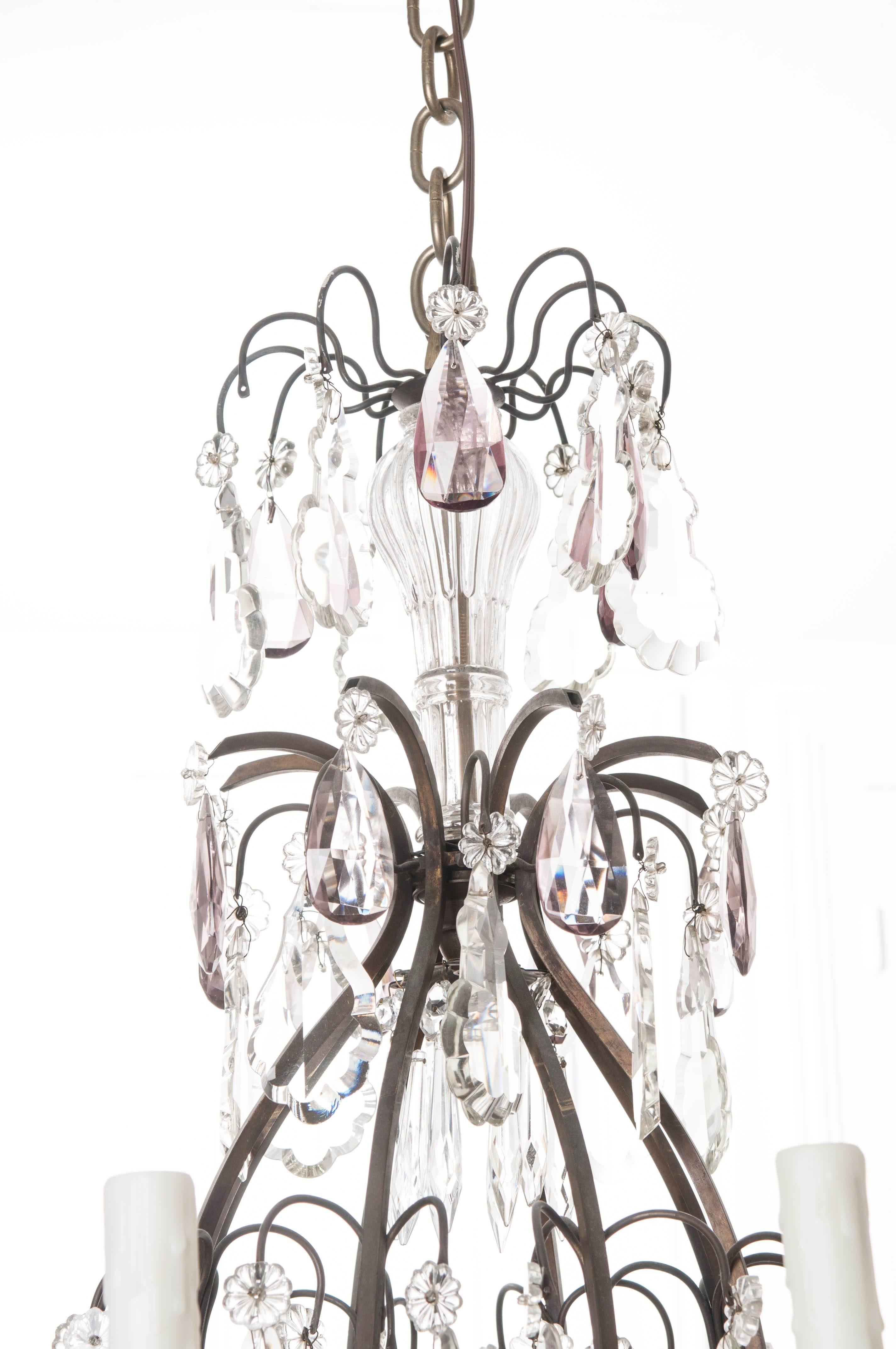 A spectacular 19th century eight light crystal chandelier from France. The metal frame is decorated with crystals, both clear and amethyst in color, and in the form of many different shapes. Each of the eight arms has an ivory candle cover that sits