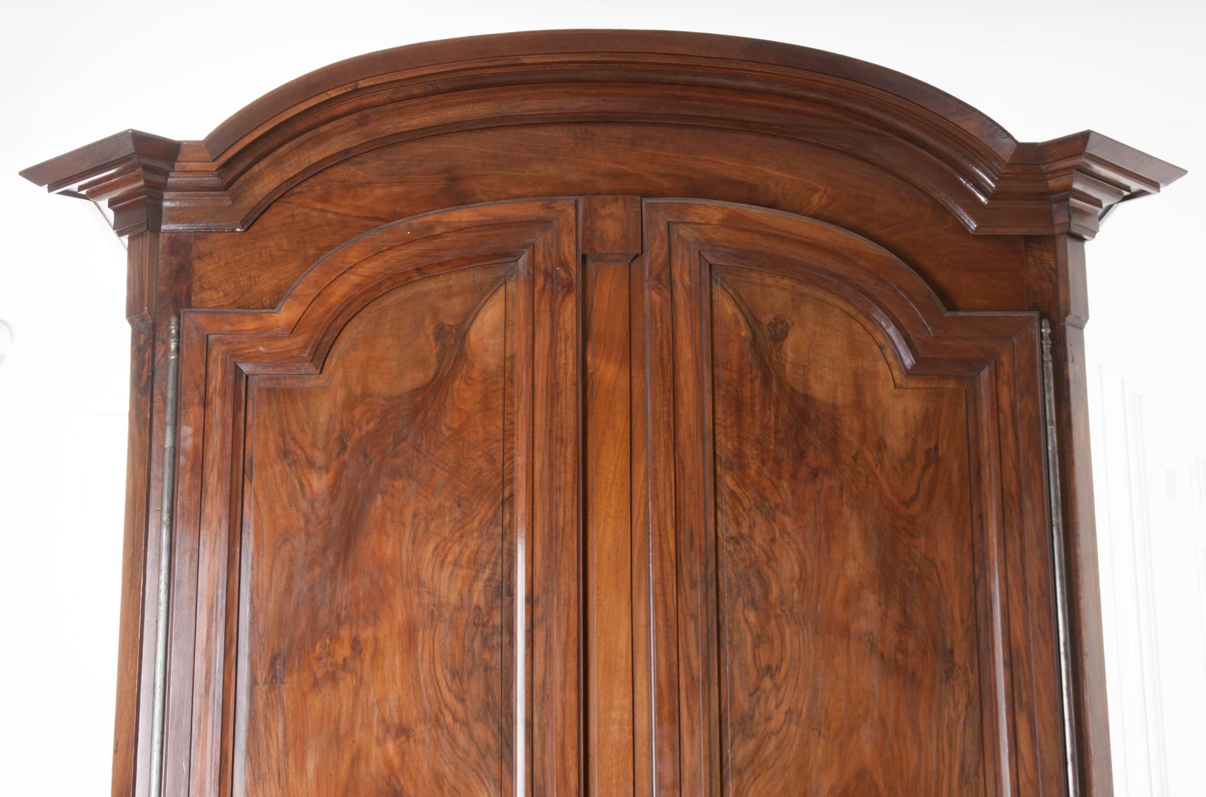 This paramount solid walnut armoire was built in France at the early part of the 19th century. A Classic Chapeau de Gendarme cornice, which essentially translates to 