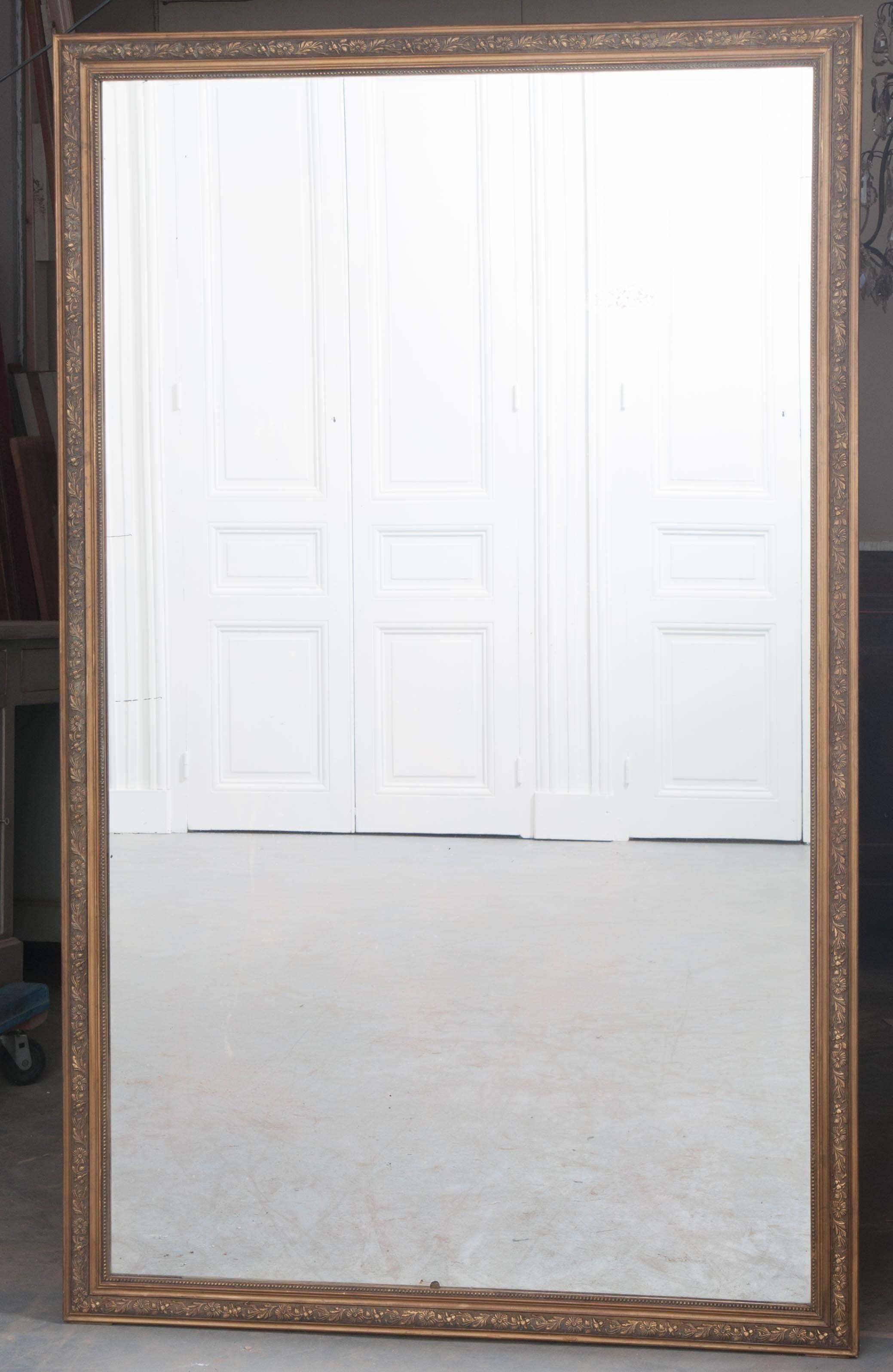 This large, rectilinear mirror dates back to 19th century, France. The frame is adorned with beaded pearl and floral motif embellishments that give the thin frame wonderful character. The frame is finished in a flat gold with an excellent antique