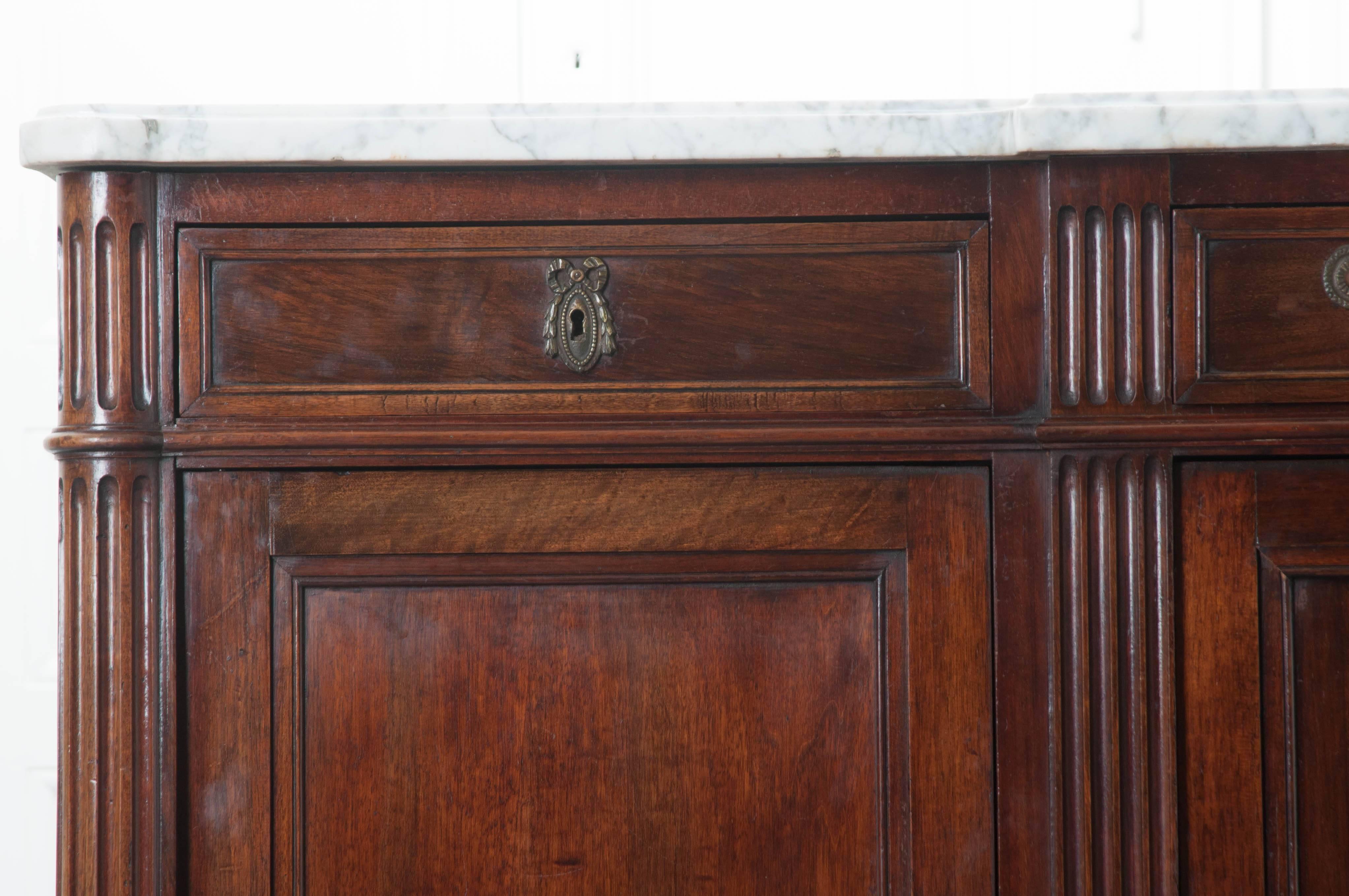 A handsome breakfront mahogany, three door Louis XVI style enfilade from 19th century, France. The antique piece is topped with its original shaped white marble. This marble top is in wonderful antique condition and is shaped to fit this enfilade.