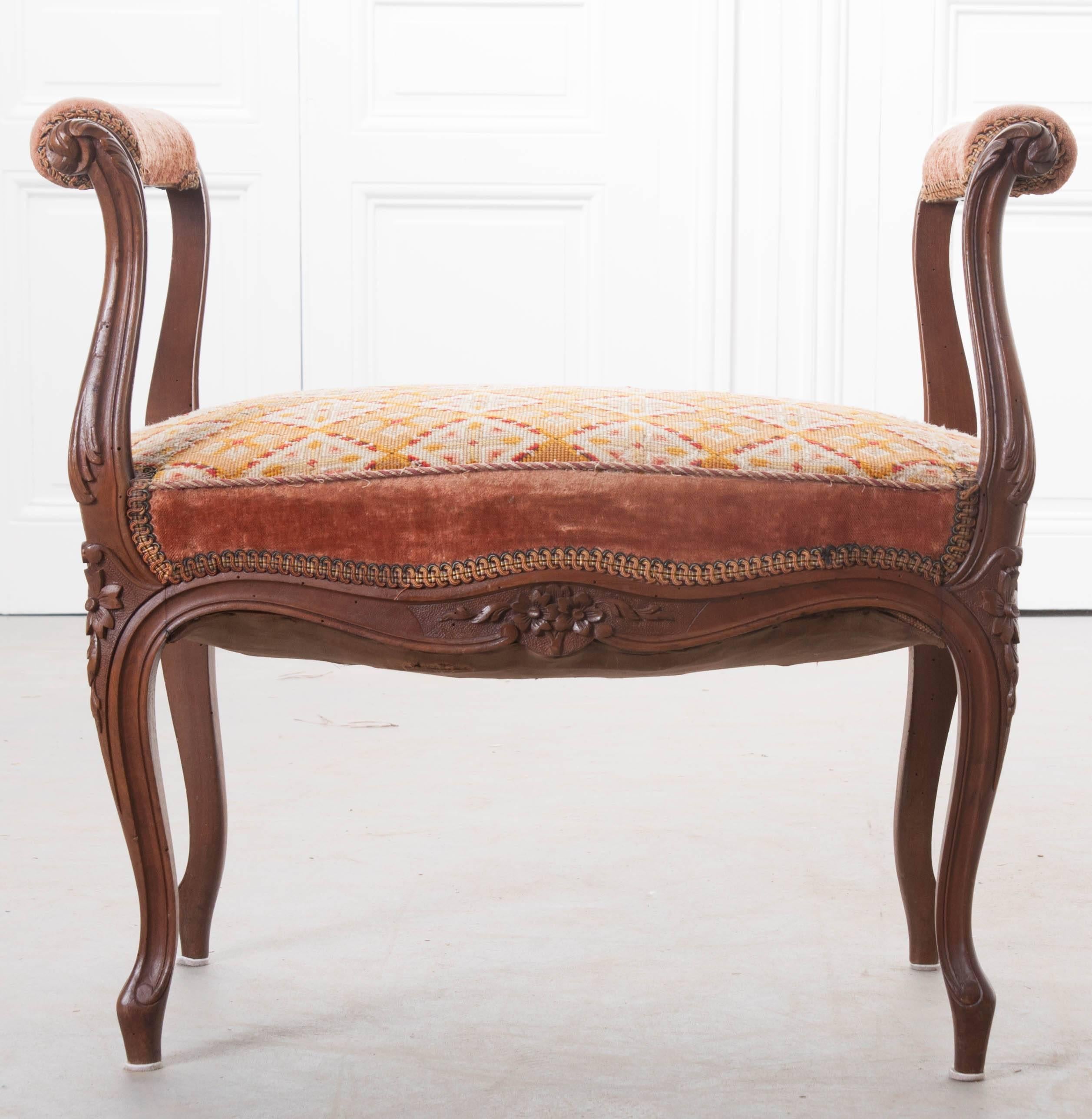 A beautifully carved French walnut Louis XV style window seat, upholstered in an original tapestry, from the 19th century. Sinuous curves and detailed floral and foliate carvings, hallmarks of Louis XV style, are expressly realized in this