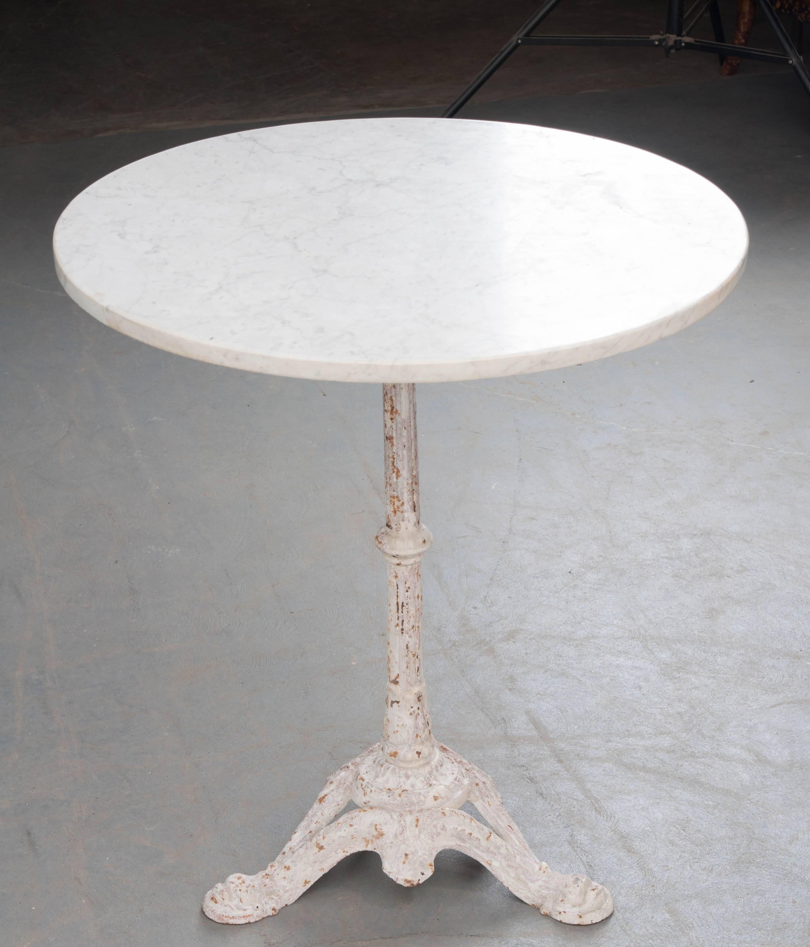 A round 19th century painted iron and marble bistro table from France. The styled iron tripod base supports the weighty top while providing decorative elements that add to the table's overall charm. The white, round marble top is in excellent