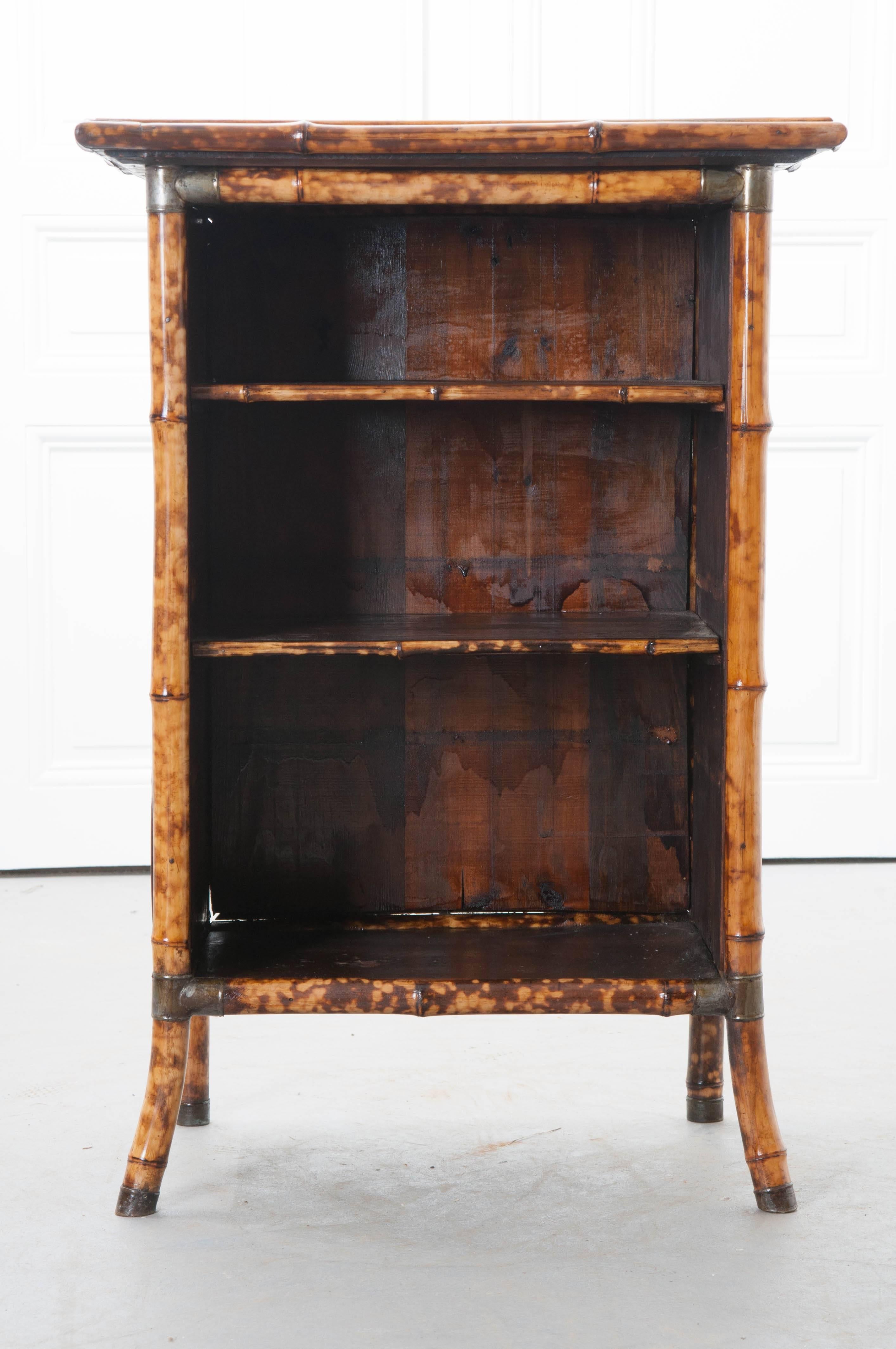 A fabulous Victorian bamboo bookcase from 19th century, England, that has been more recently decoupaged with an assortment of beautiful gold colored shells on its top and sides. This bookcase has metal reinforced corners for added stability and