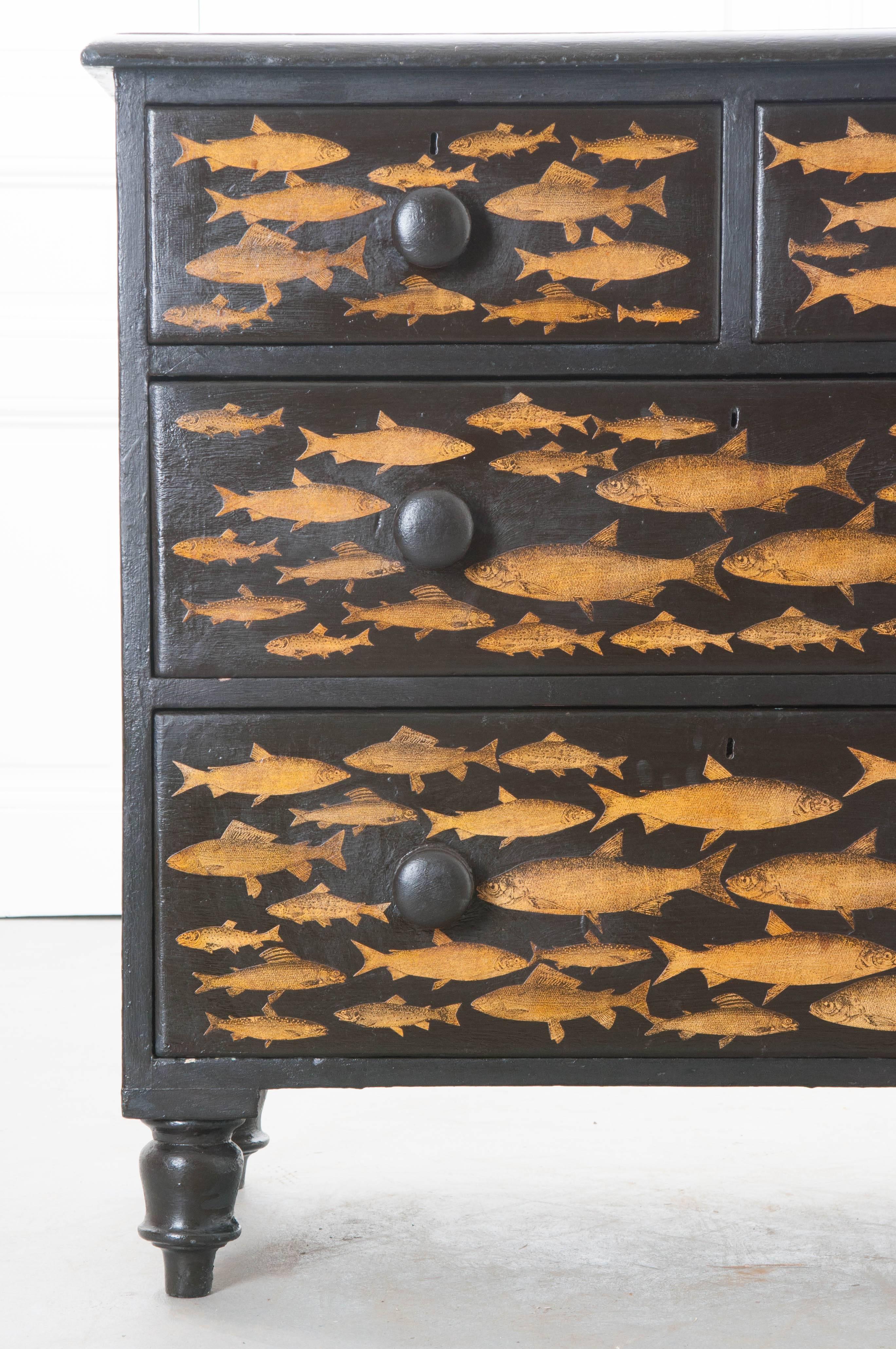 A Victorian, painted four-drawer chest of drawers from 19th century England, that has more recently had wonderful gold fish decoupaged onto the piece. Each drawer has turned, wooden knobs that have also been painted black. The linear, restrained