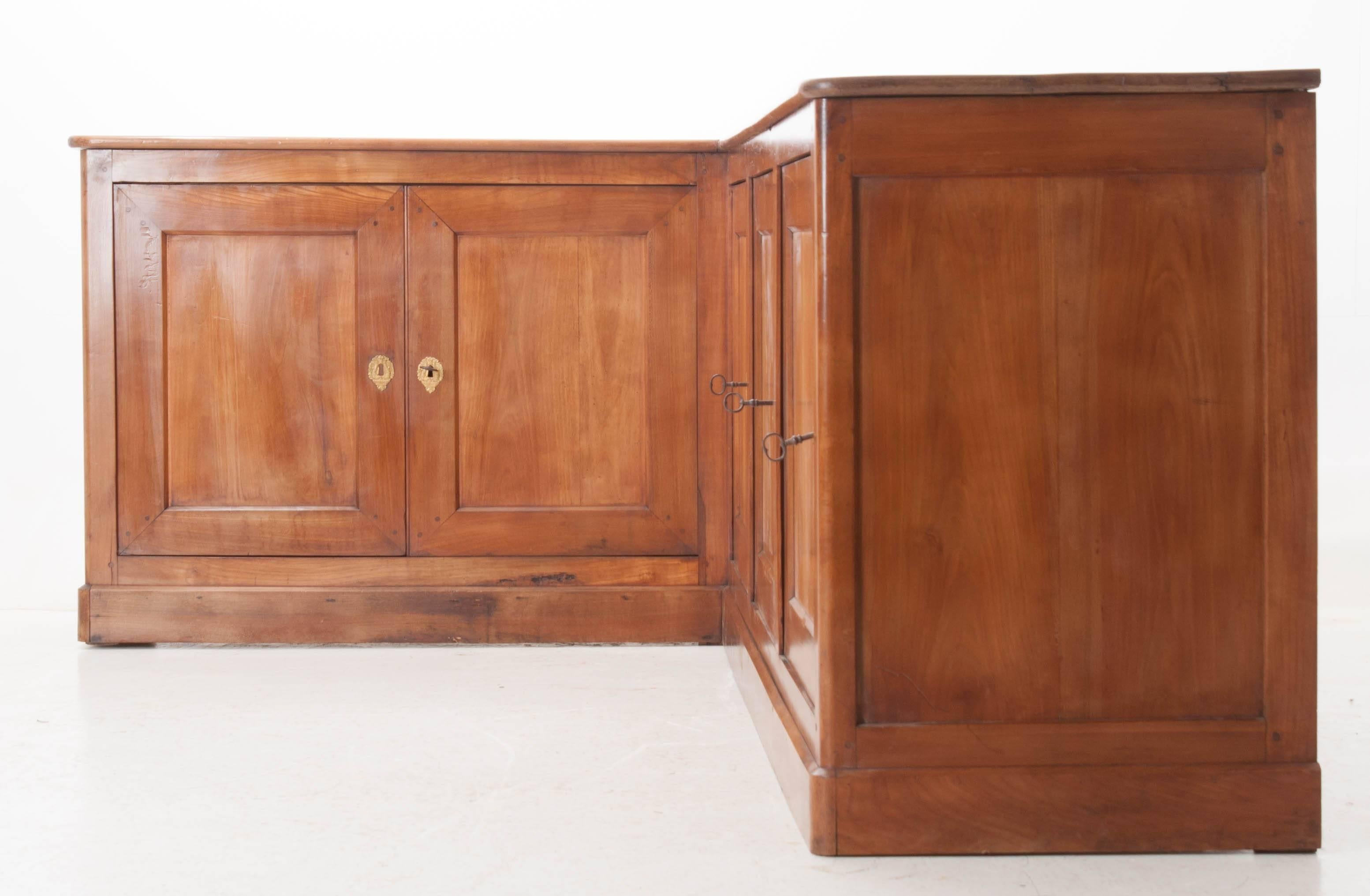 A beautiful, large French 19th century cherry Louis Philippe corner enfilade. Five lockable doors with decorative brass escutcheons are hung on hidden hinges. These doors conceal the interior cavities that provide abundant storage. These are