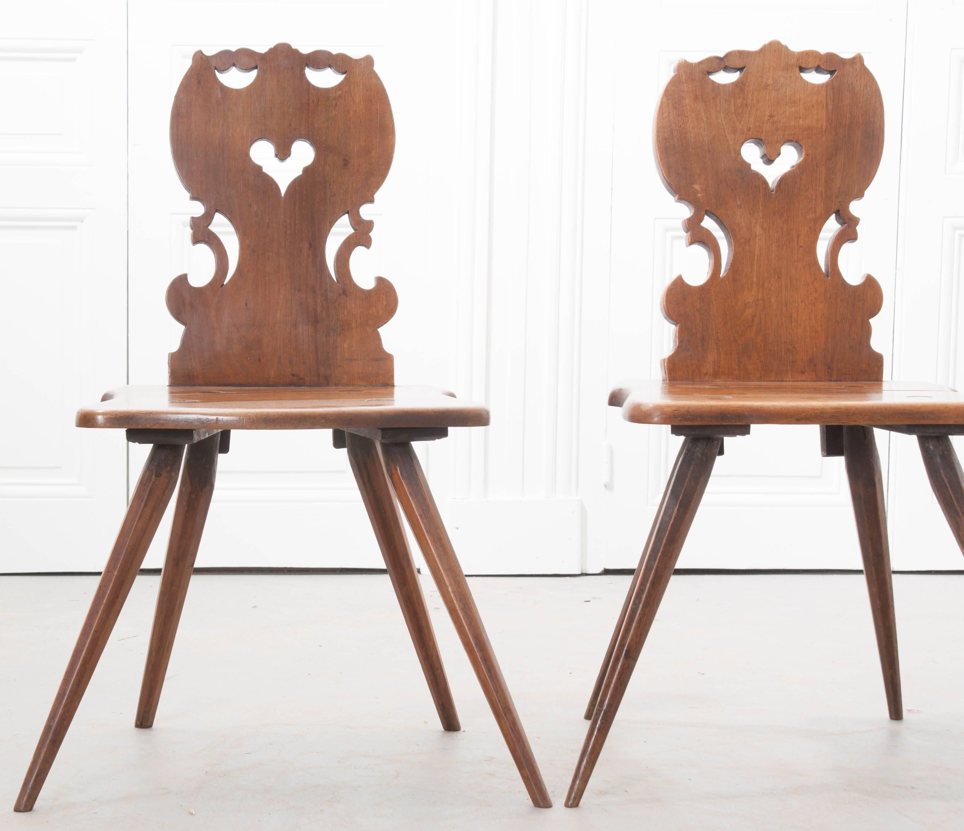 A spectacular pair of hand-carved chairs from the Alsace region of France, circa 1820. The back rests are pierced, with sweet, heart imagery, and made from carefully selected, thick plank boards of walnut. The seats are shaped, to which the faceted