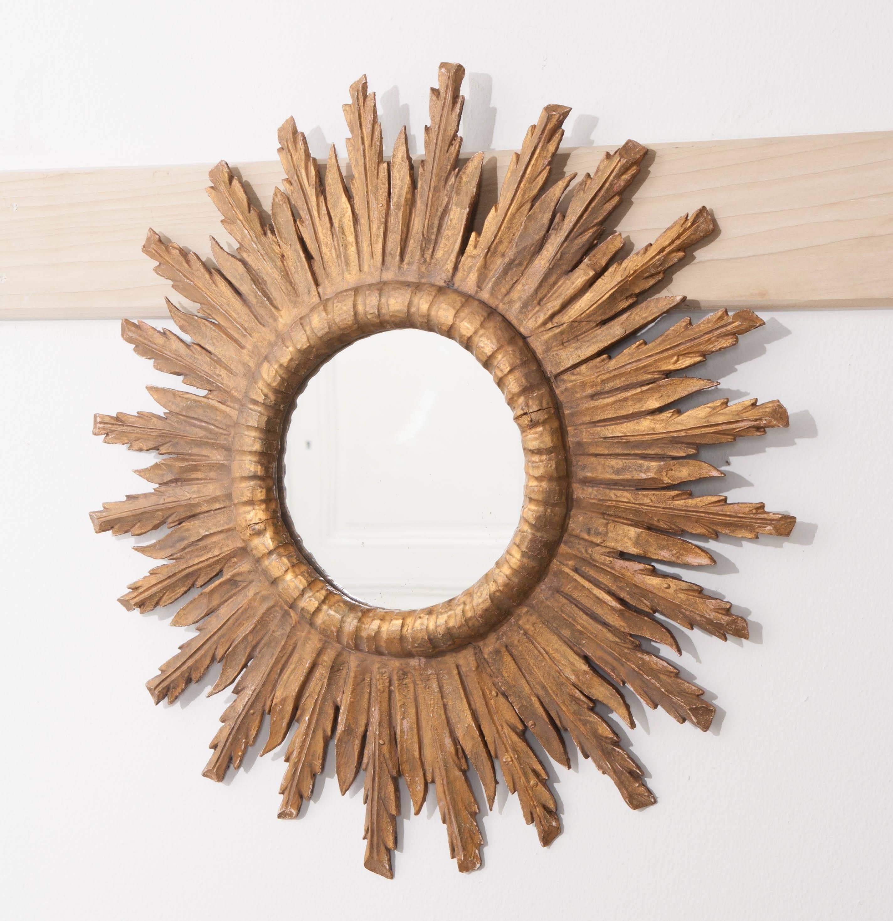 A fine hand-carved 19th century giltwood starburst mirror from France. The circular mirror has its original glass, with some signs of foxing. Sunbeams radiate from the central mirror in staggering lengths, adding depth, and giving this fabulous
