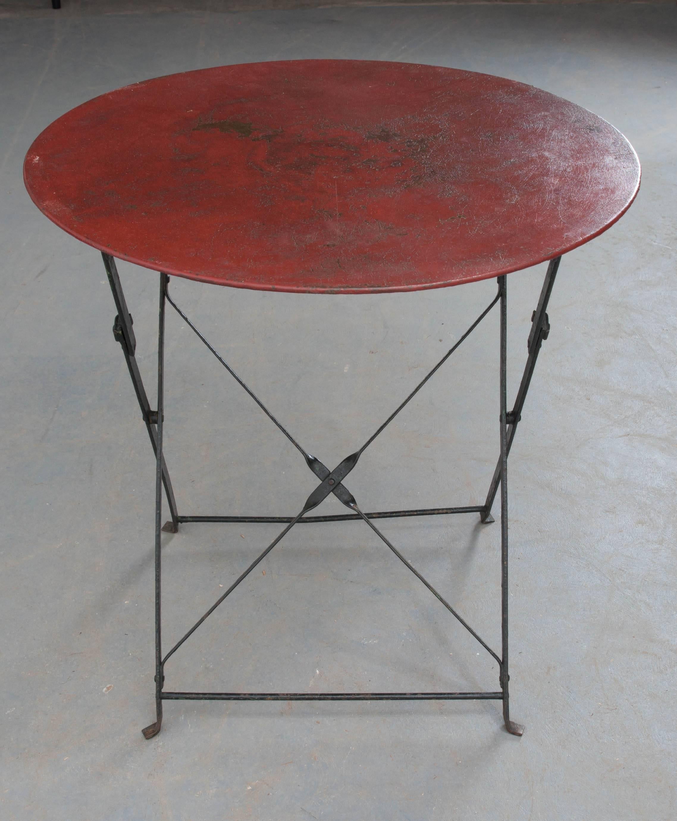 An excellent round, folding metal garden table from England, circa 1920. The red painted top makes quite a statement for this fun outdoor antique. With the ability to fold up for easy moving and storage, this little table will be perfect for parties