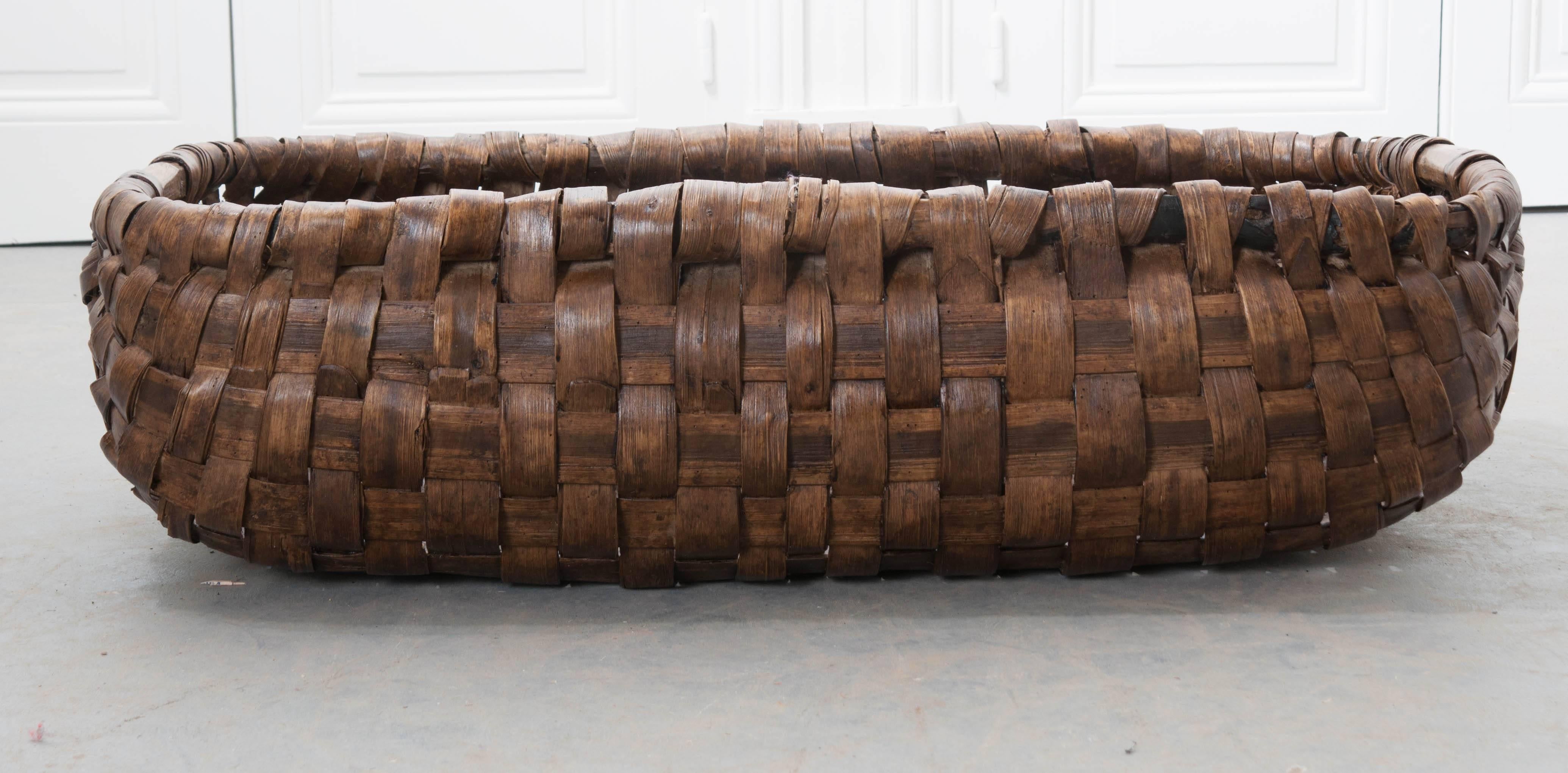 This incredible, woven basket was made in Normandy, France, towards the end of the 19th century. These large baskets were used while harvesting apples from the orchard. This basket is very well constructed, with carefully woven thick rattan bands