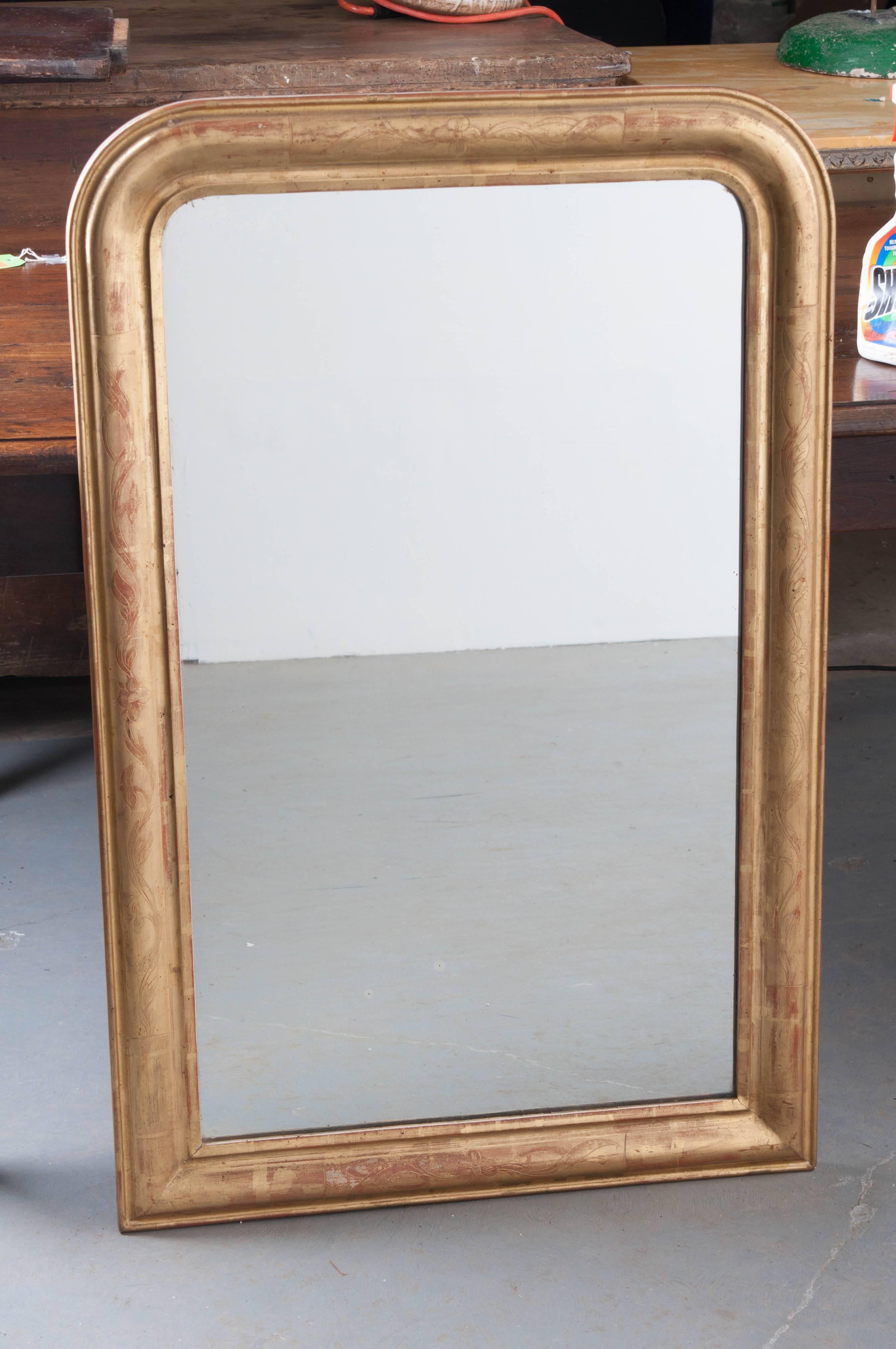 This fantastic, purely Louis Philippe gold gilt mirror was made circa 1870 in France. Radiant gold gilt engulfs the frame, with just the right amount of the red, bole substratum visible about the mirror. The gilt work is garnished with flowering