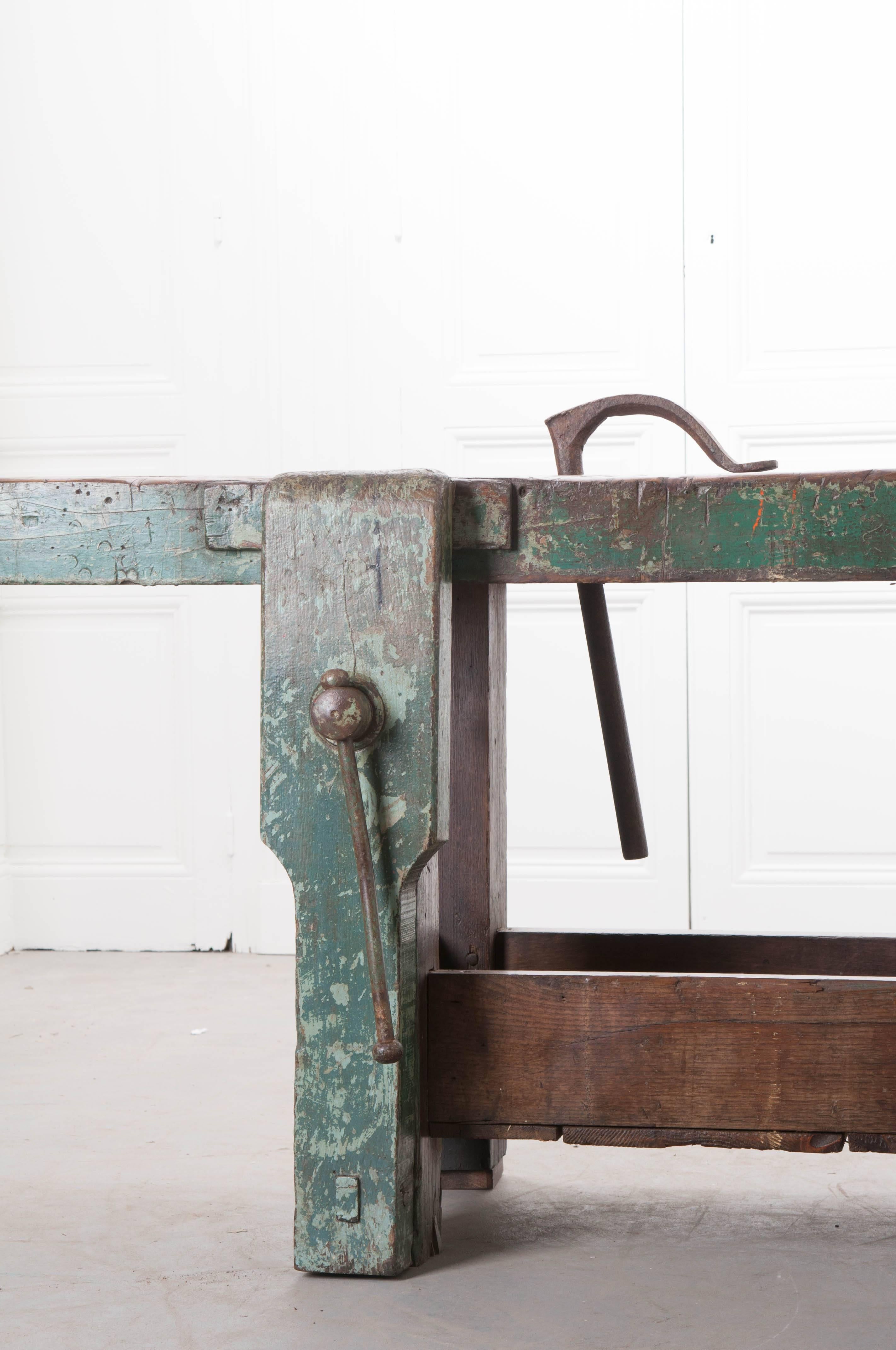 Numerous projects have been completed over the years using this painted 19th century English workbench. Deep marks are scored into every inch of the work surface, left there by the saws of craftsmen from long ago. Interesting features include a