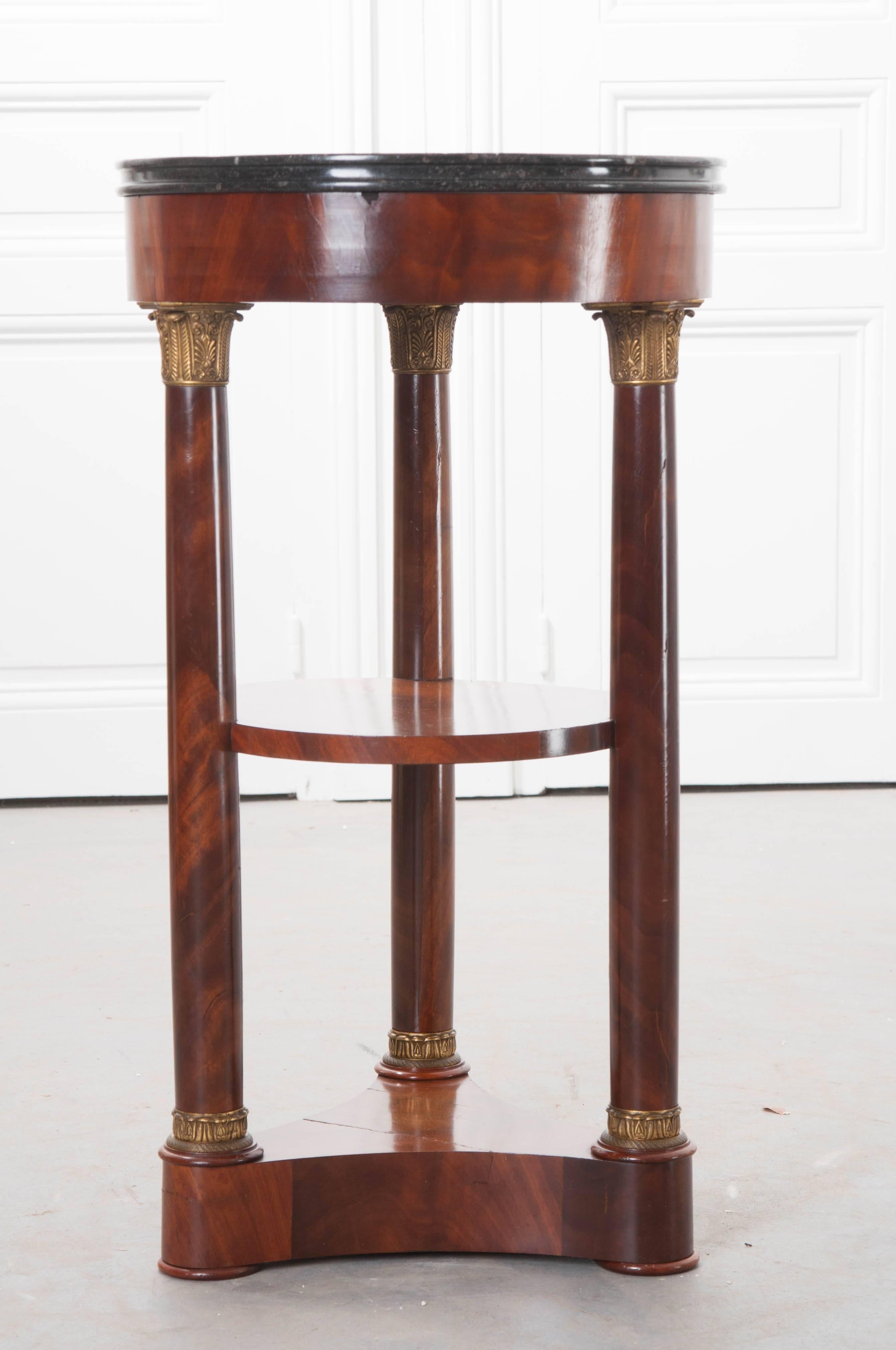 A remarkable round, mahogany table with marble top, from the Empire period, France. This wonderful table has a round, black, fossil marble top. This marble top has a finished edge and is in excellent condition. The table has three legs, all with