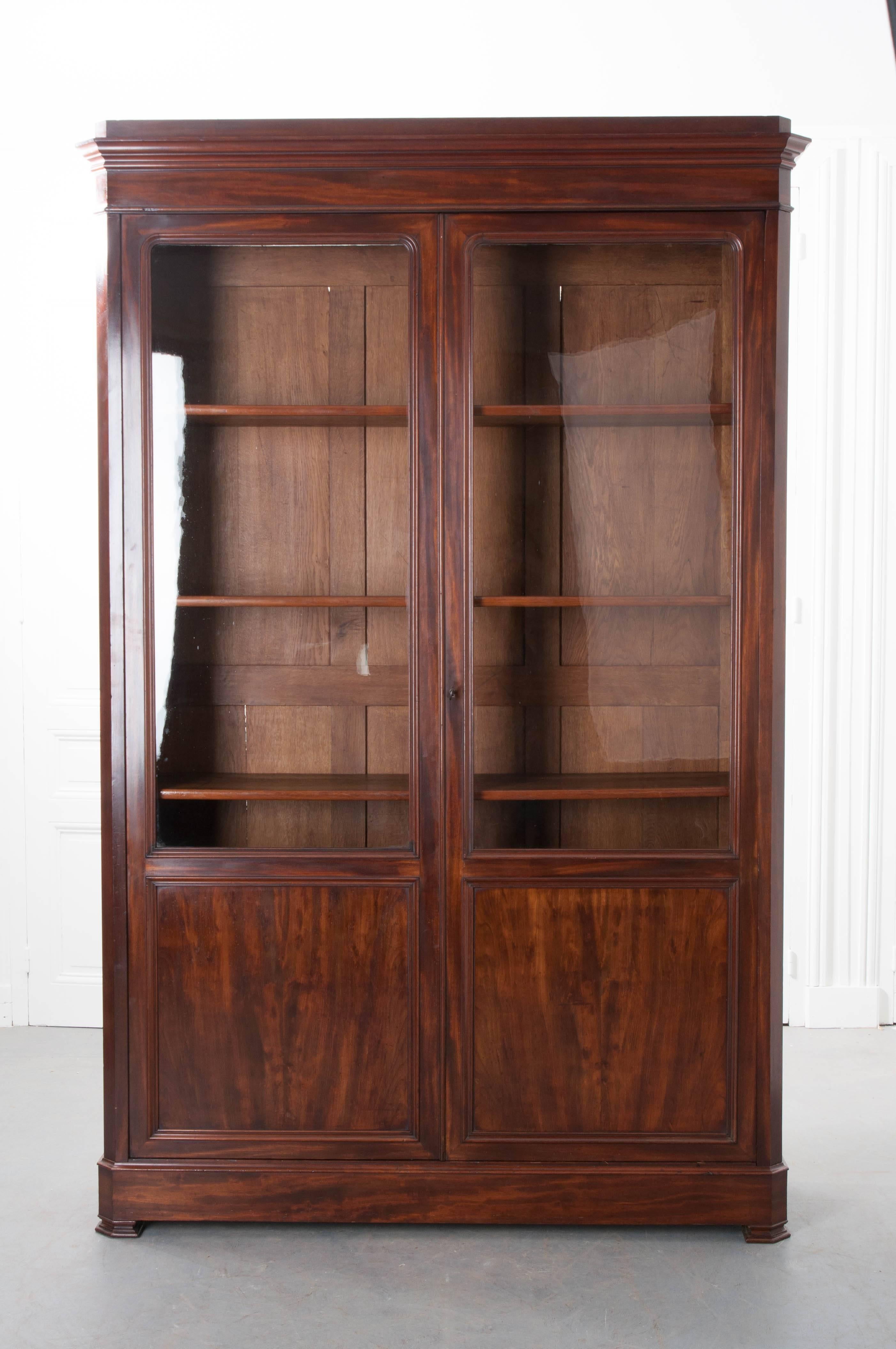 A handsome French Louis Philippe bibliothèque, made of mahogany, from the latter part of the 19th century. The bookcase has two glass front doors, which can be locked, that close before the antique's interior. The doors have large windows that have