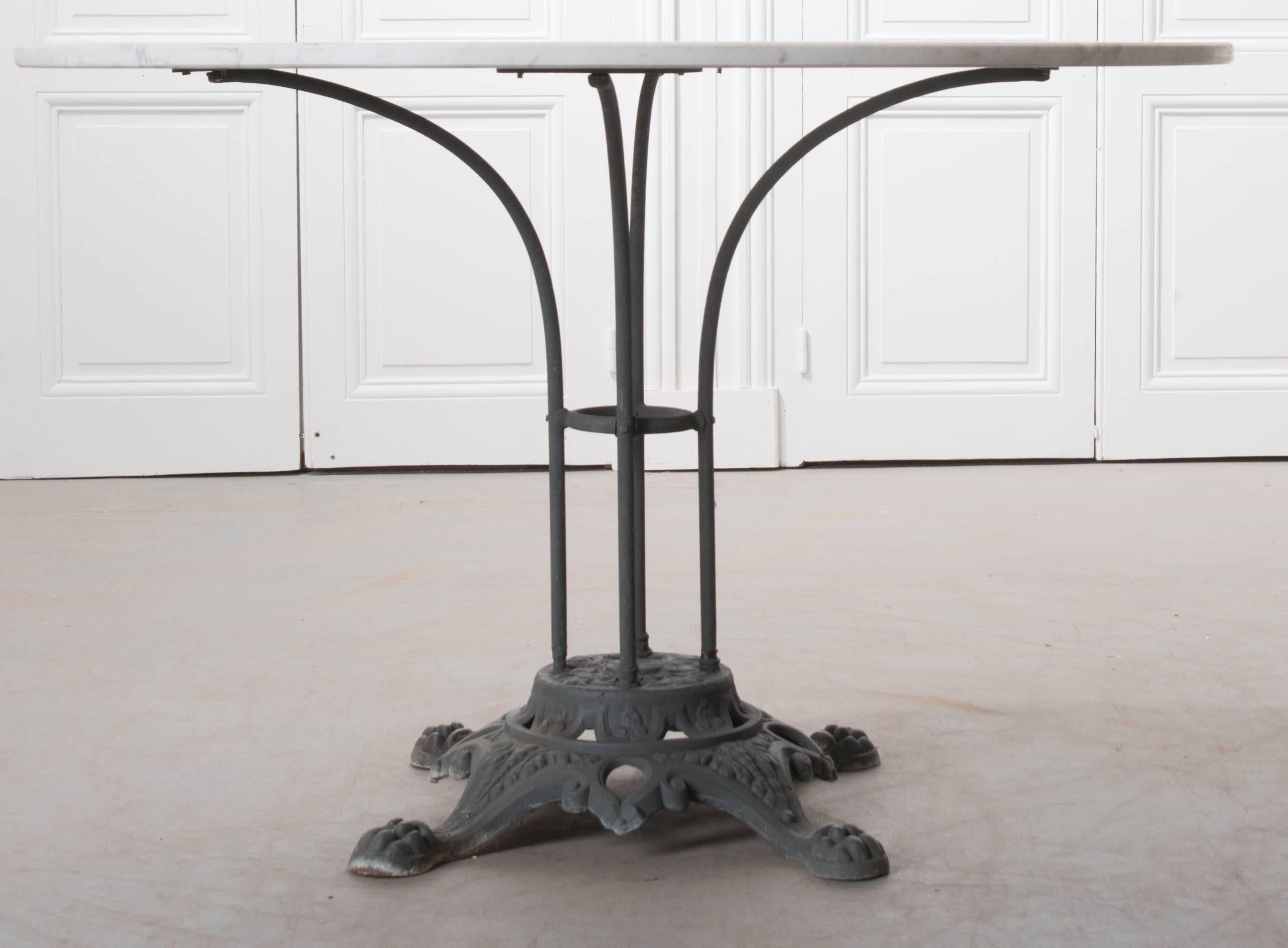 A wonderful cast iron garden table with white marble top from early 20th century, France. The table has a cast iron pedestal base, with four paw feet adding to the styling of this iron foundation. From this extend four tubular, vertical iron