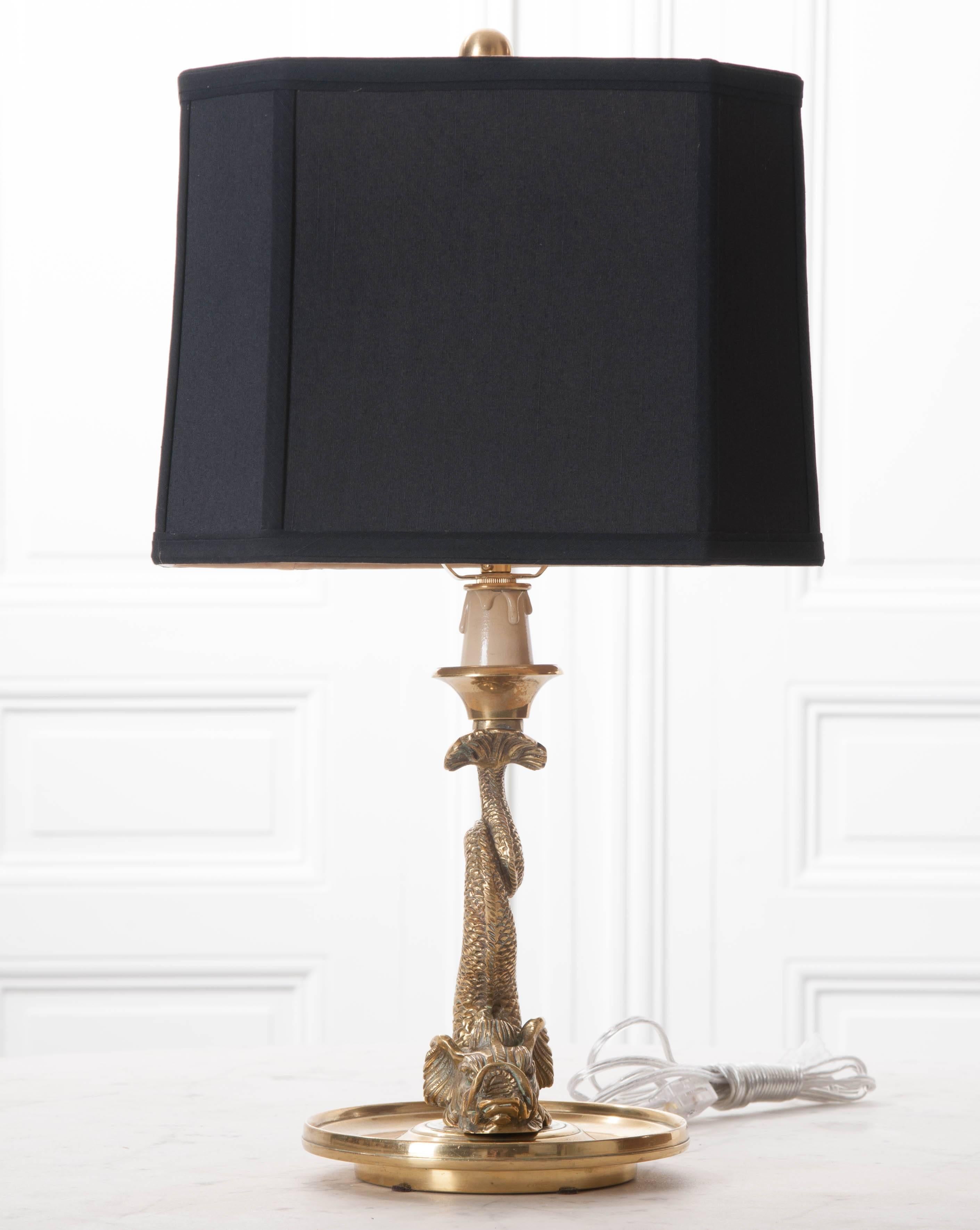A gorgeous French brass lamp, done in a dolphin motif, with black silk shade. The fish’s head is near the base of the lamp, which has a dish-shaped form, ideal for catching spare change and other loose ends. The sinuous fish loops its scaly body,