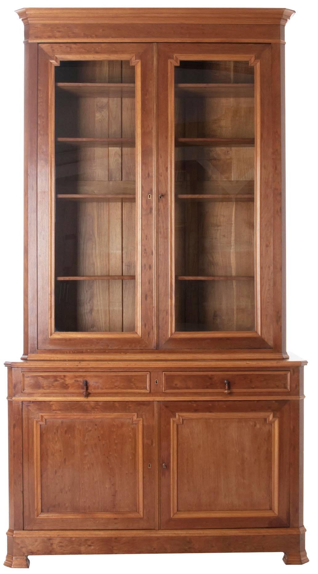 French Louis Philippe bibliotheque in bird's-eye mahogany. Wonderful crown over bibliotheque of two glass locking doors over its buffet of two drawers and two doors. Four adjustable shelves in top and one fitted shelf in bottom, behind closed doors.