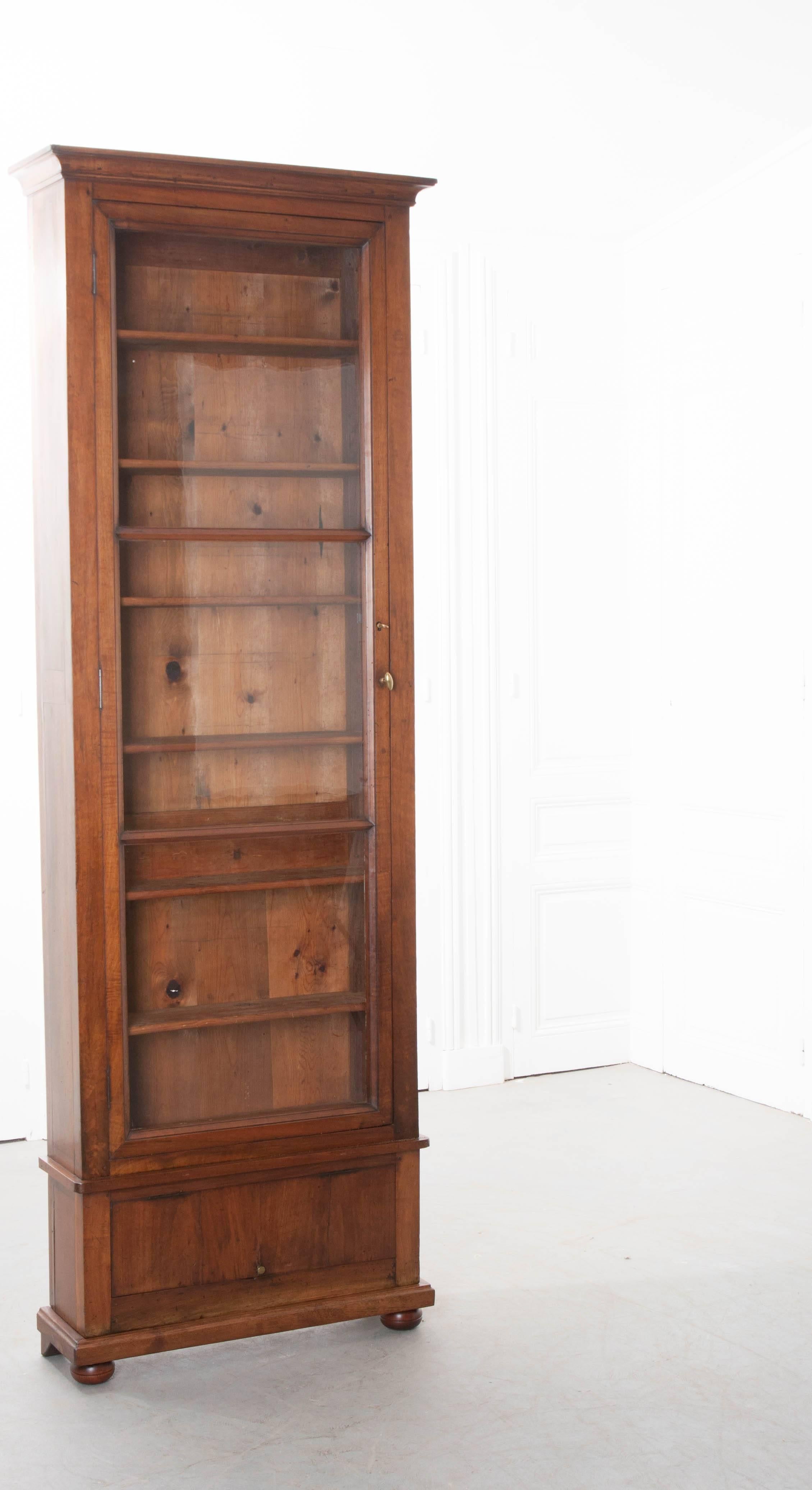 This remarkable walnut bibliothèque is a 19th century French creation. The single door bibliothèque has its original wavy glass from top to bottom. The door has a working lock and brass knob that will secure it with a simple twist. The interior has