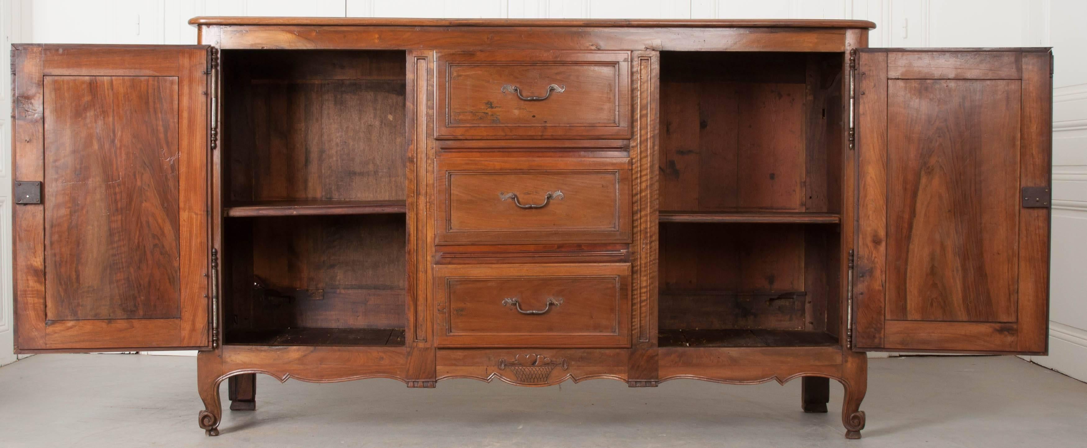 A fantastic French 19th century cherry enfilade with three drawers found between its two doors. The cherry is beautifully toned with a rich warm color. Elements of both Louis XV and Provincial styles are present in this transitional antique. The top