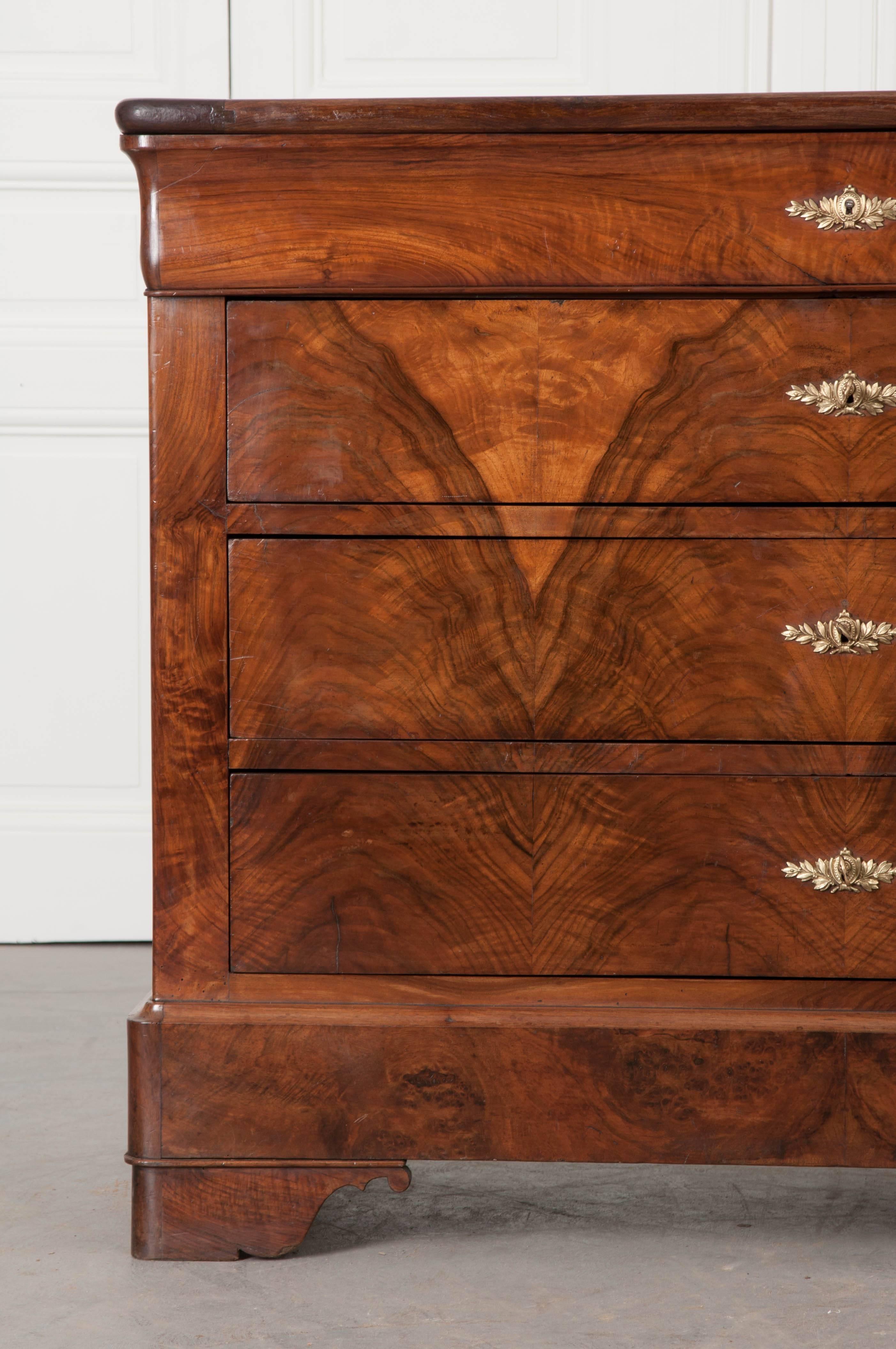 Beautifully book matched burl mahogany veneer graces the façade of this stunning 19th century Louis Philippe four drawer commodes. The top is gorgeous, with rounded front corners that match the body. The topmost drawer has a shaped front that