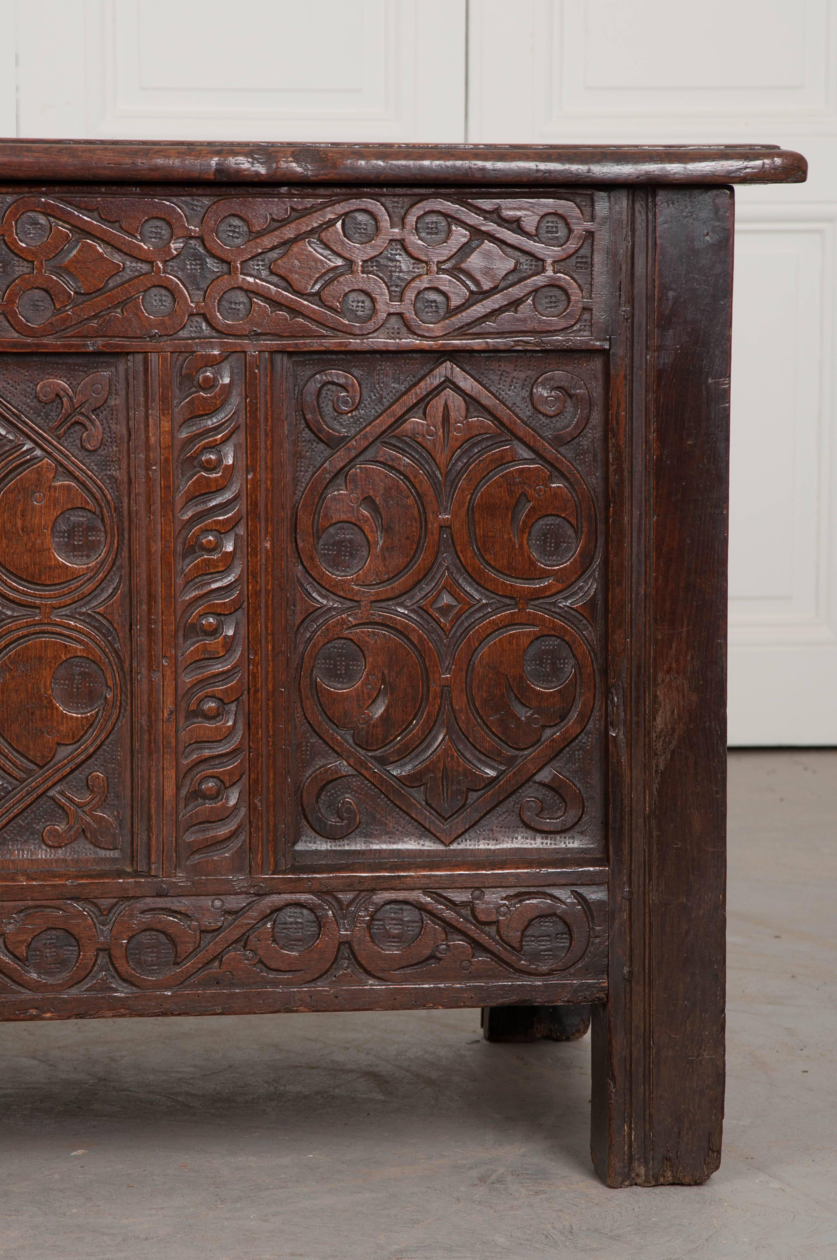 A gorgeous coffer or trunk from the late 1700s, England. The façade has four panels that have been meticulously carved into patterns of scrolls, hearts, leaves, and geometric shapes. The lid and sides are designed with more simple, framed panels.
