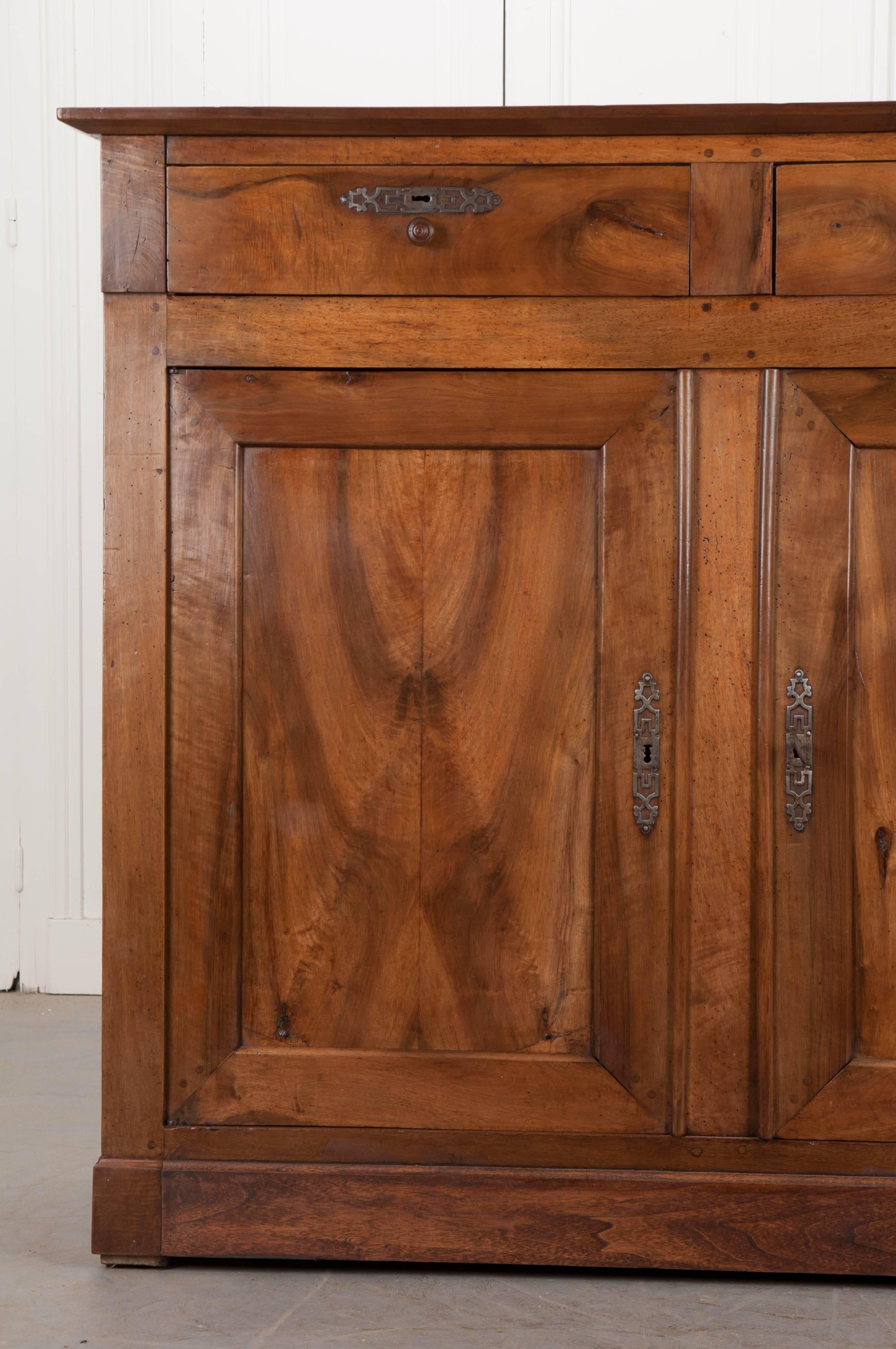 A fantastic tall buffet, made of solid walnut, from provincial France, circa 1880. The two drawers have turned wood knobs and patinated cut steel escutcheons. The doors also have cut steel escutcheons, a working lock, and they close before a