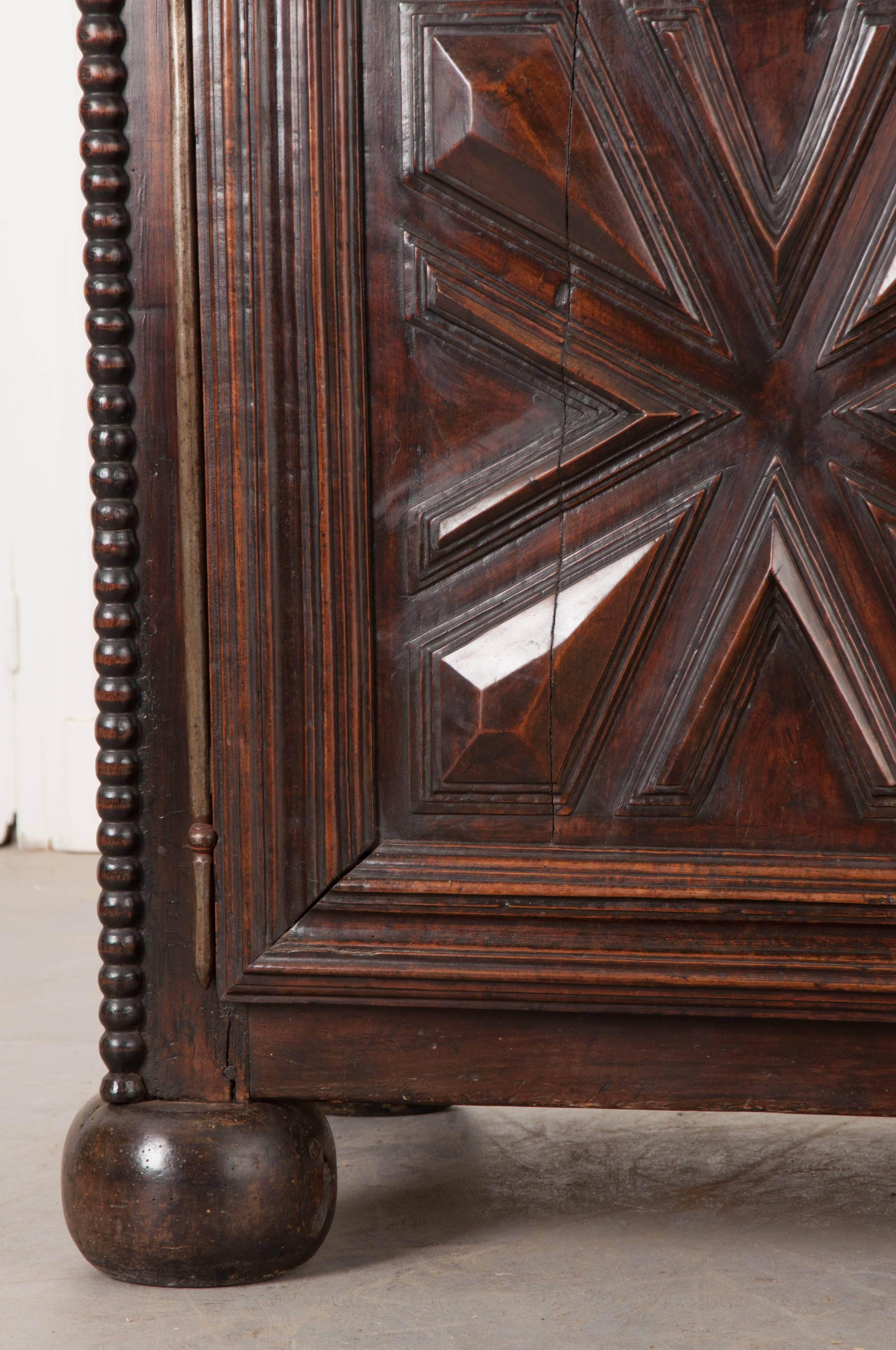 A sizable oak buffet, done in the Louis XIII style, from 18th century France. This tall case piece features extraordinary hand-carved panels, in a geometric style, found in its doors and sides. The two drawers as well as the two doors have wonderful