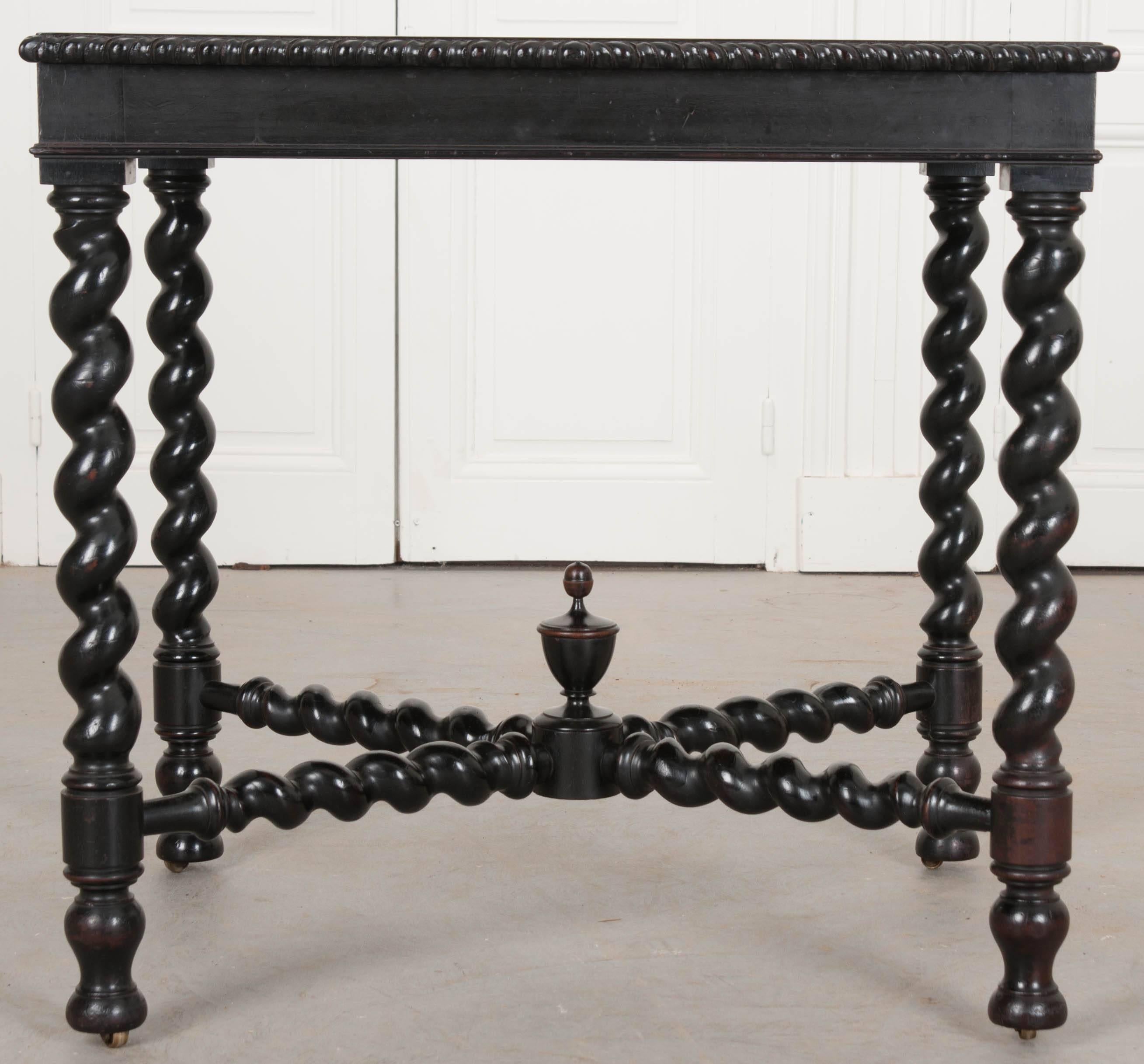 A striking Italian ebony table, made in the 19th century, with an inset top of rust-colored Scagliola stone. The table top is trimmed in a mirrored carved twist motif that runs the entire perimeter. The table’s most noticeable feature is the barley