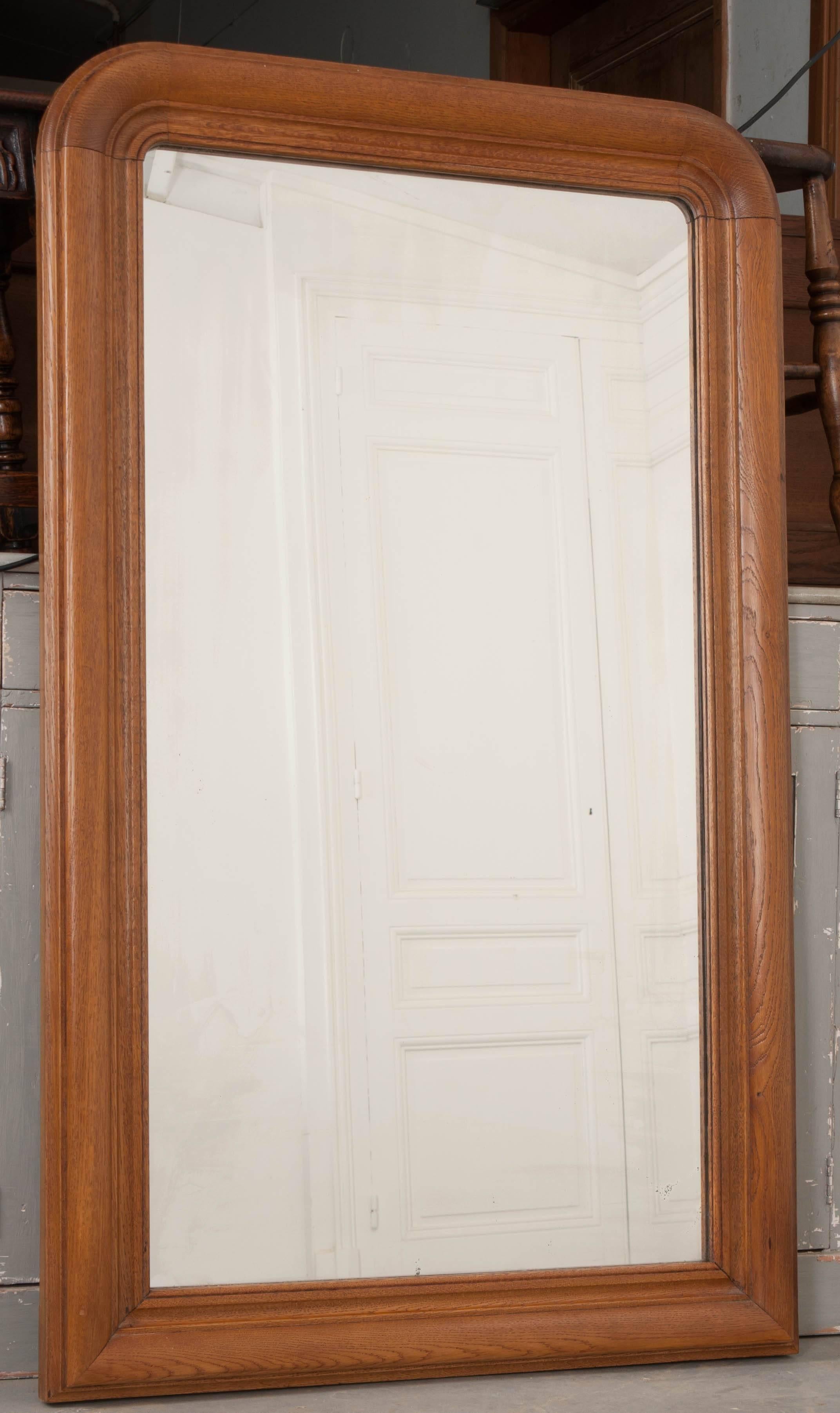 A classic Louis Philippe mirror from 19th century, France, with carved oak frame and original glass. Often finished in a metallic gilt, this unique antique mirror has been left in its natural state, with extraordinary patina acquired from years of