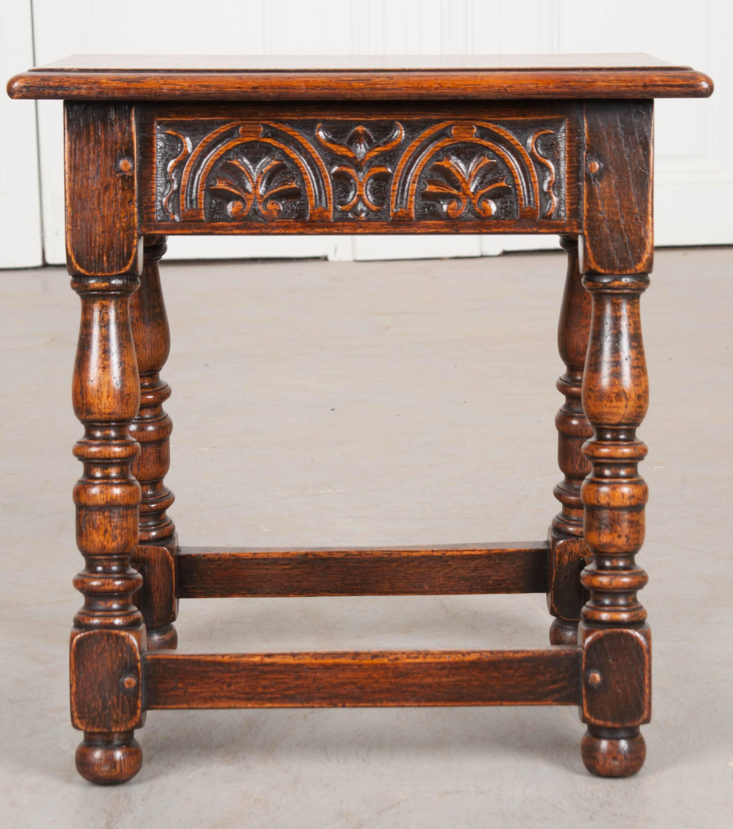 A fantastic little oak stool, carved by hand in England, circa 1890. The apron is particularly special with this antique in that it is wonderfully carved, with symmetrical arched horseshoes on all sides. The legs are beautifully turned in a