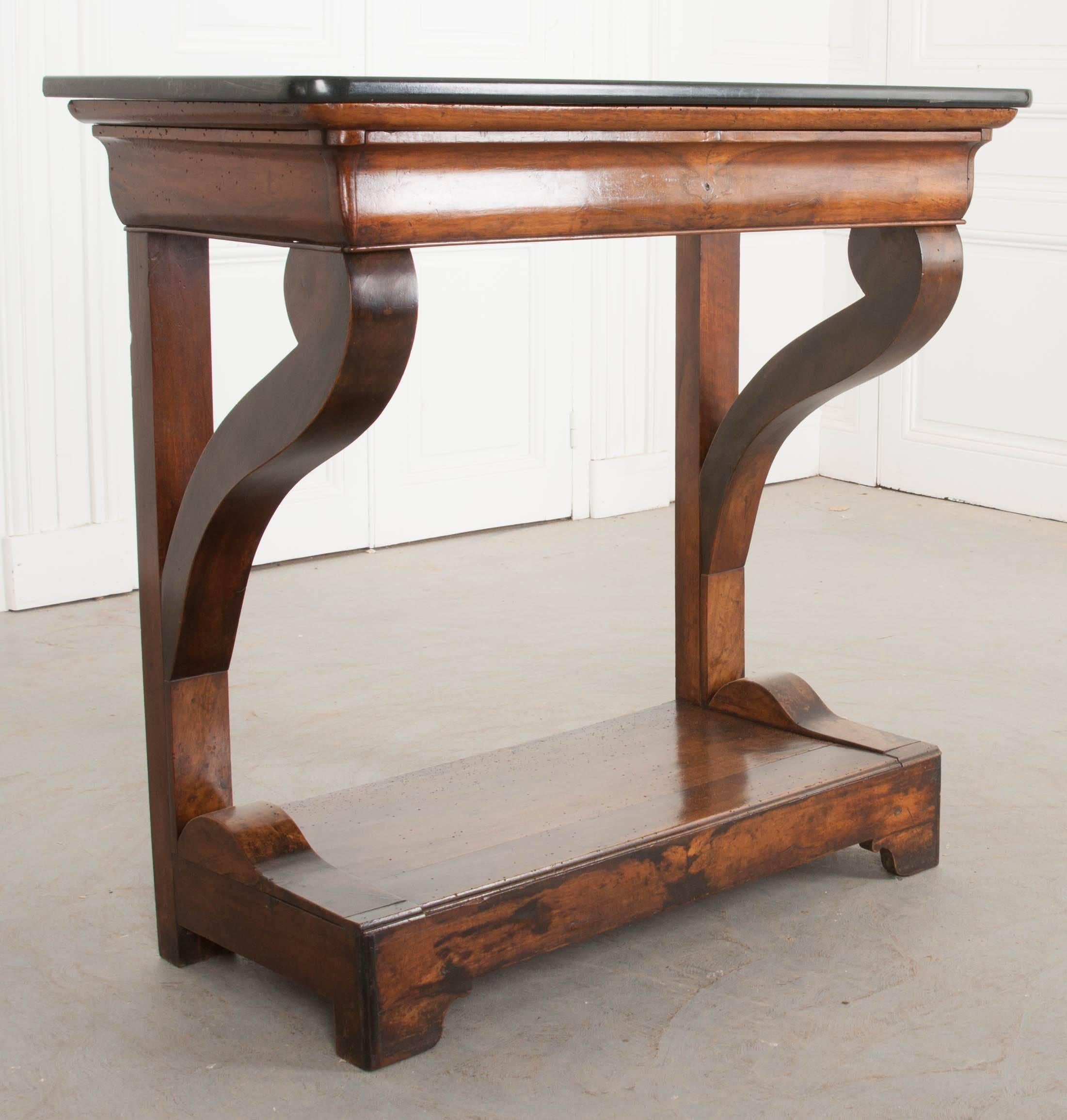 This gorgeous marble-top walnut console was made in France around the middle of the 19th century. The black marble top has rounded front corners and is original to the console. Below the marble, a hidden drawer exists in the table’s shaped apron.