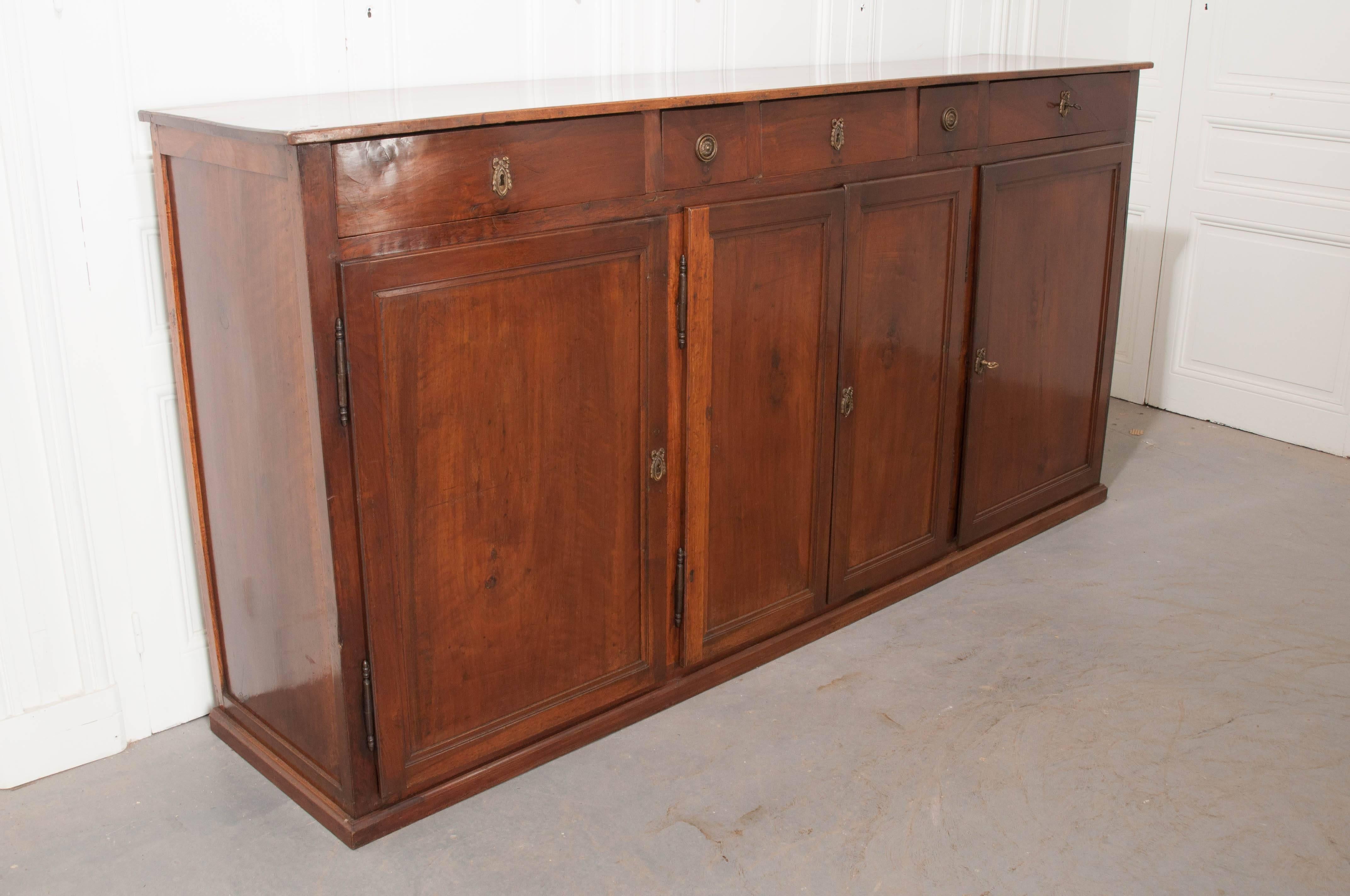 A sizable mahogany sideboard from 19th century England. This four-door case piece features three interior storage cavities as well as five drawers, and has been influenced by the French Louis XVI style. All doors and drawers that are lockable