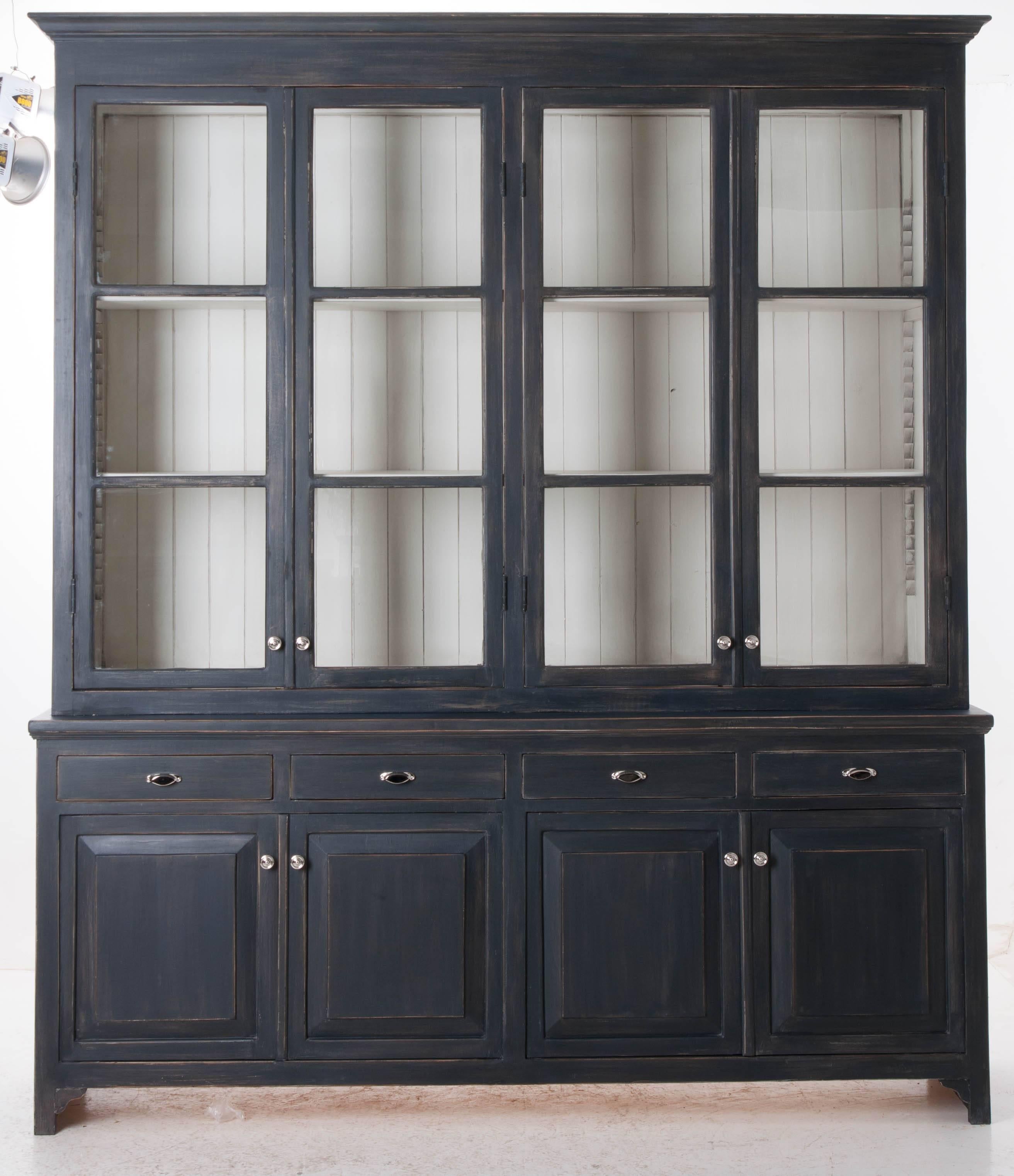 This custom eight door bibliotheque has four glass front upper doors that close before two adjustable shelves. The base has four drawers set above four doors that conceal one adjustable shelf. Bibliotheques are great for both displaying your