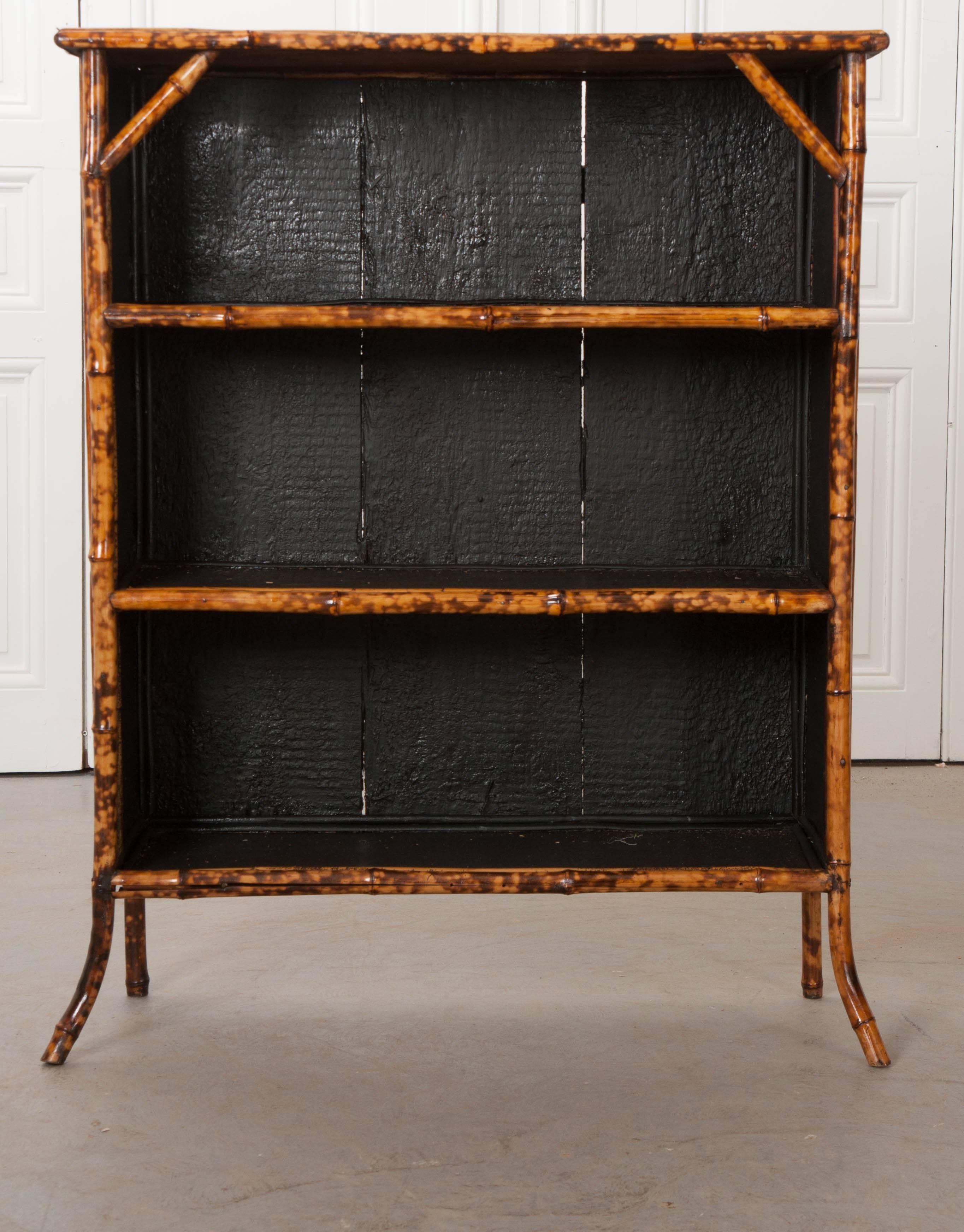 An antique English bamboo bookshelf from the 1890s, that has been recently refinished. Where you see black and découpage is where seagrass would have been. Over time, the seagrass has been damaged and recently replaced with this fabulous fish
