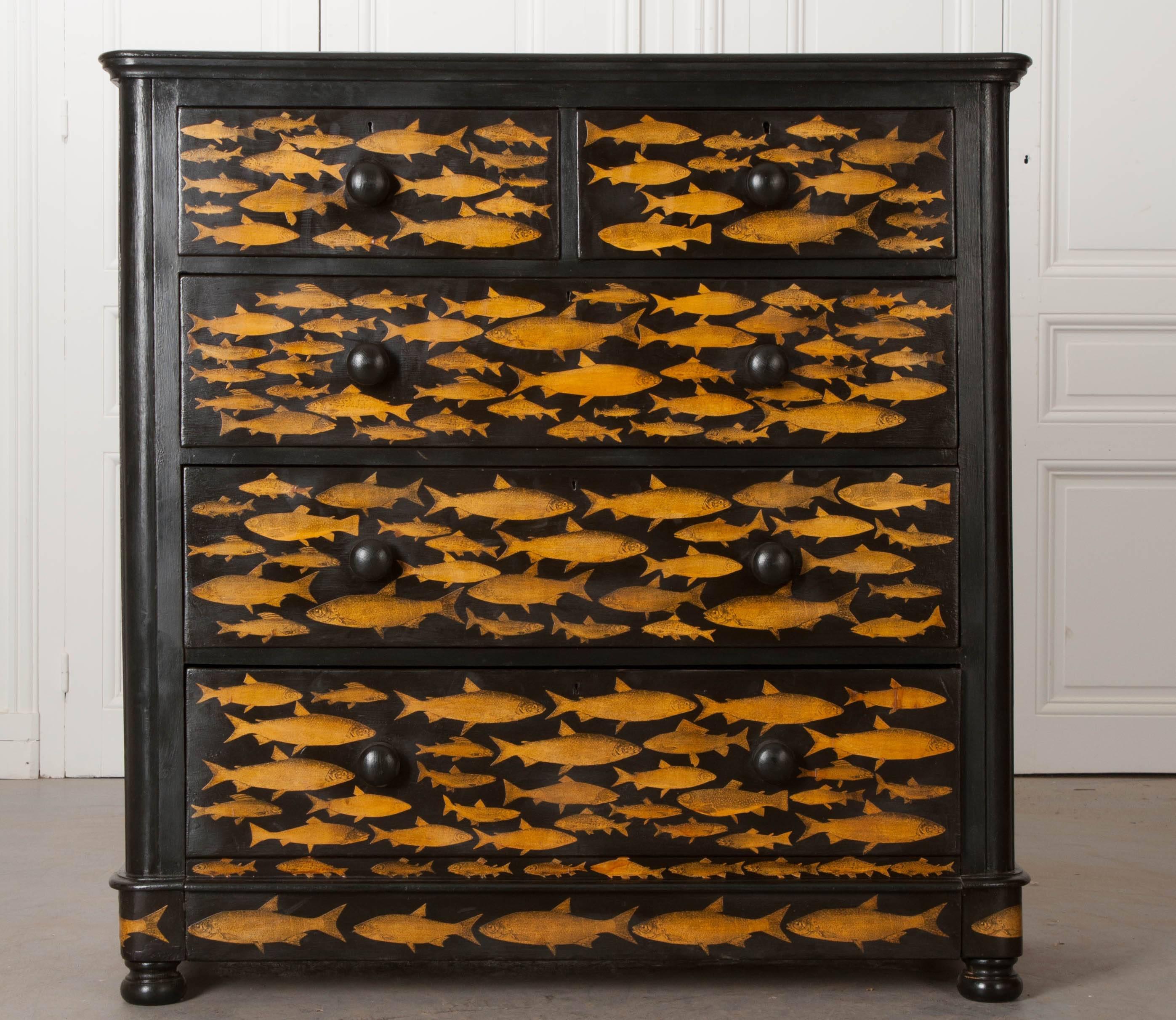 A Victorian, painted five-drawer chest of drawers from 19th century England, that has more recently had wonderful gold fish decoupaged onto the piece. Each drawer has turned, wooden knobs that have also been painted black. The linear, restrained