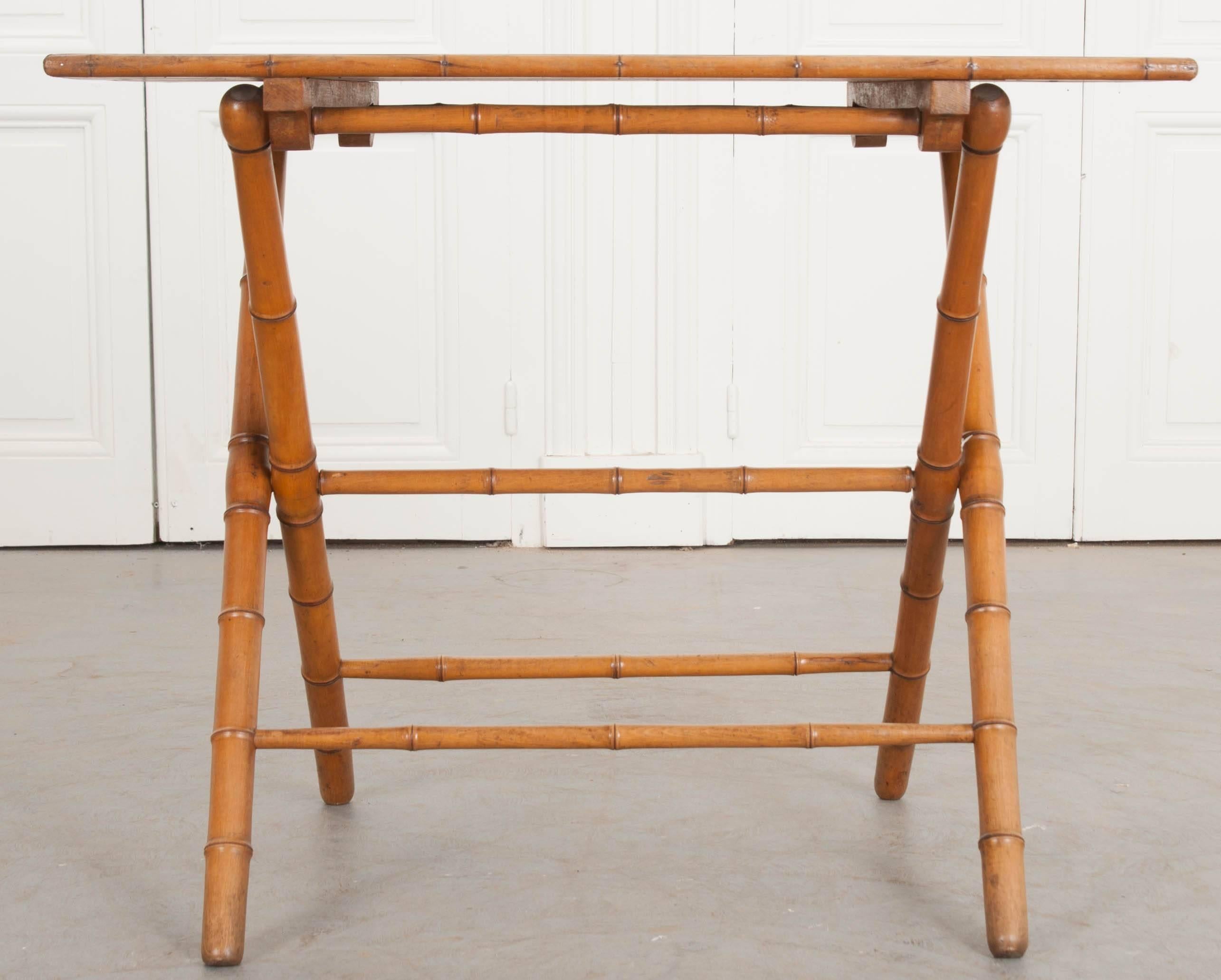 An attractive folding coaching table made of pine and cherry, from the turn of the century, England. The table has a pine top that is encased by a band of cherry faux carved bamboo. The base is also made of cherry and carved to resemble bamboo. A