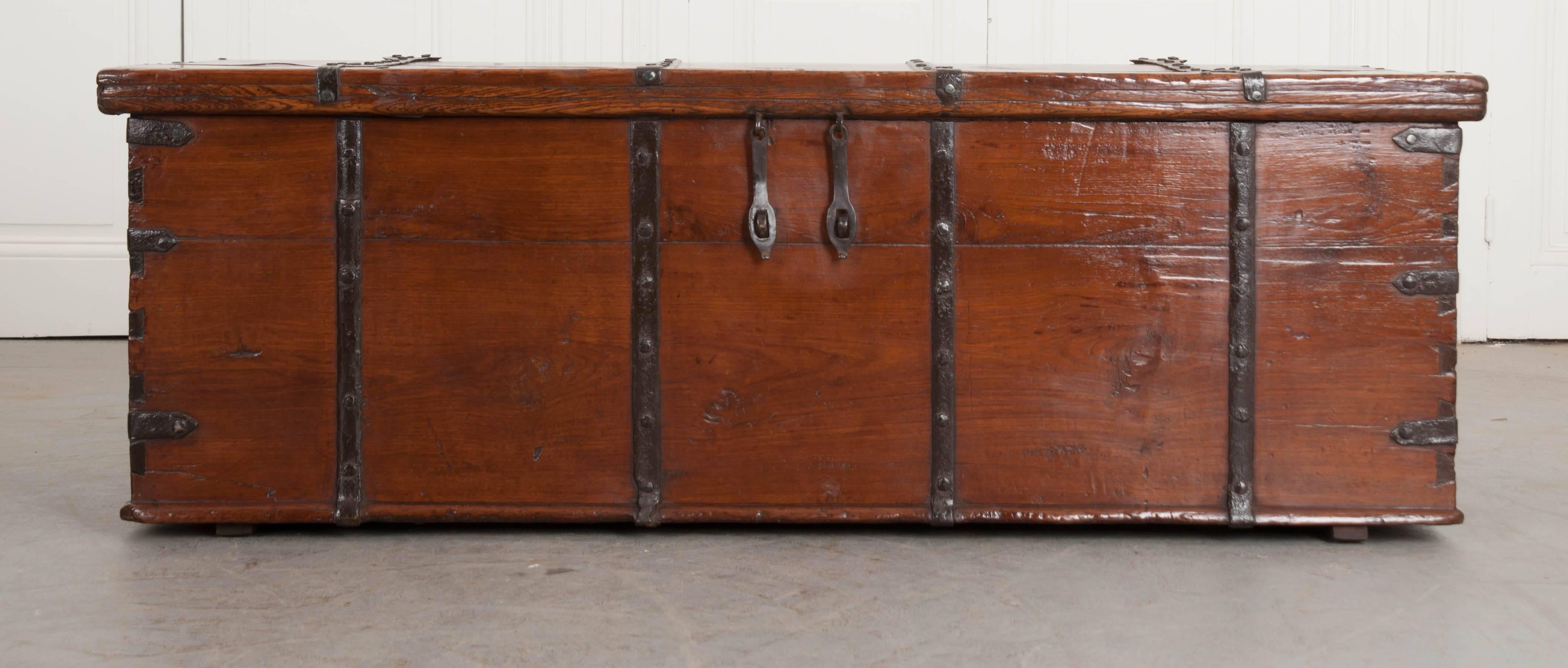 A fabulous solid-teak 19th century Anglo-Indian iron strapped trunk circa 1860. The antique chest was constructed using teak with iron banding wrapping the entire piece. Teak is resilient in hot and humid climates, and was the preferred wood used