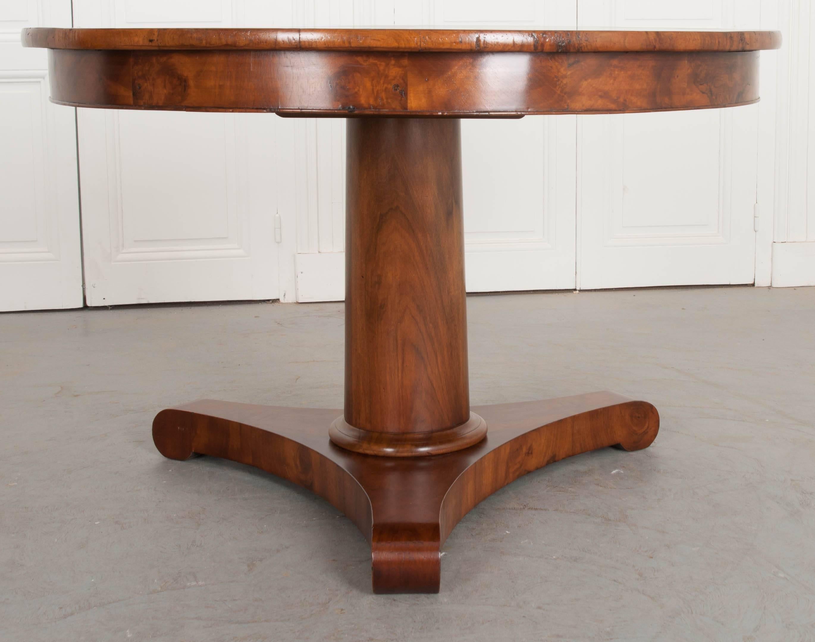 A spectacular large walnut center table, with pedestal base, from 19th century, France. An extraordinary concave tripod base supports the table’s wide vertical column shaft. Both the base and shaft have been carefully bookmatched. The table’s top is