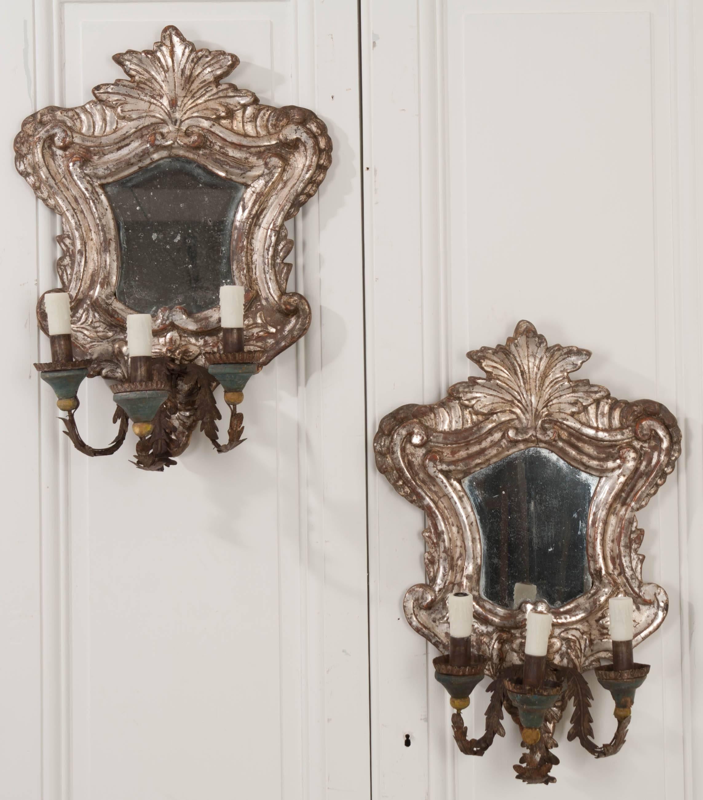 An elegant pair of silver gilt three-light sconces from Italy, circa 1780. These beautifully carved sconces have been made in the Rococo style, with beautiful silver gilt that is still largely intact. The pair contain shaped mirrors, that, along