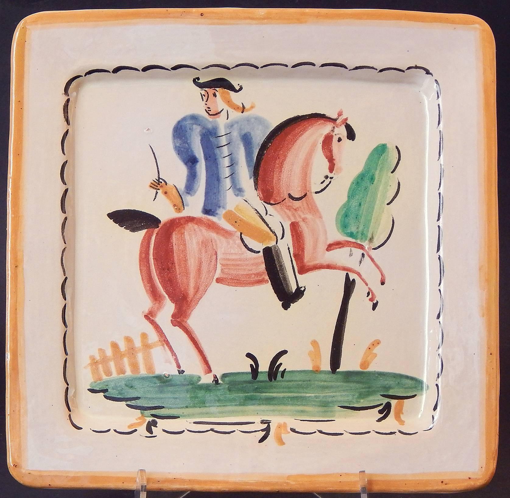 Painted with freshness and sophistication, this pair of Italian Art Deco plates depict elegant, stylized horses, one ridden by a blue-coated man in a bicorn hat and another pair standing regally by a fence and tree. The palette -- ocean blue,