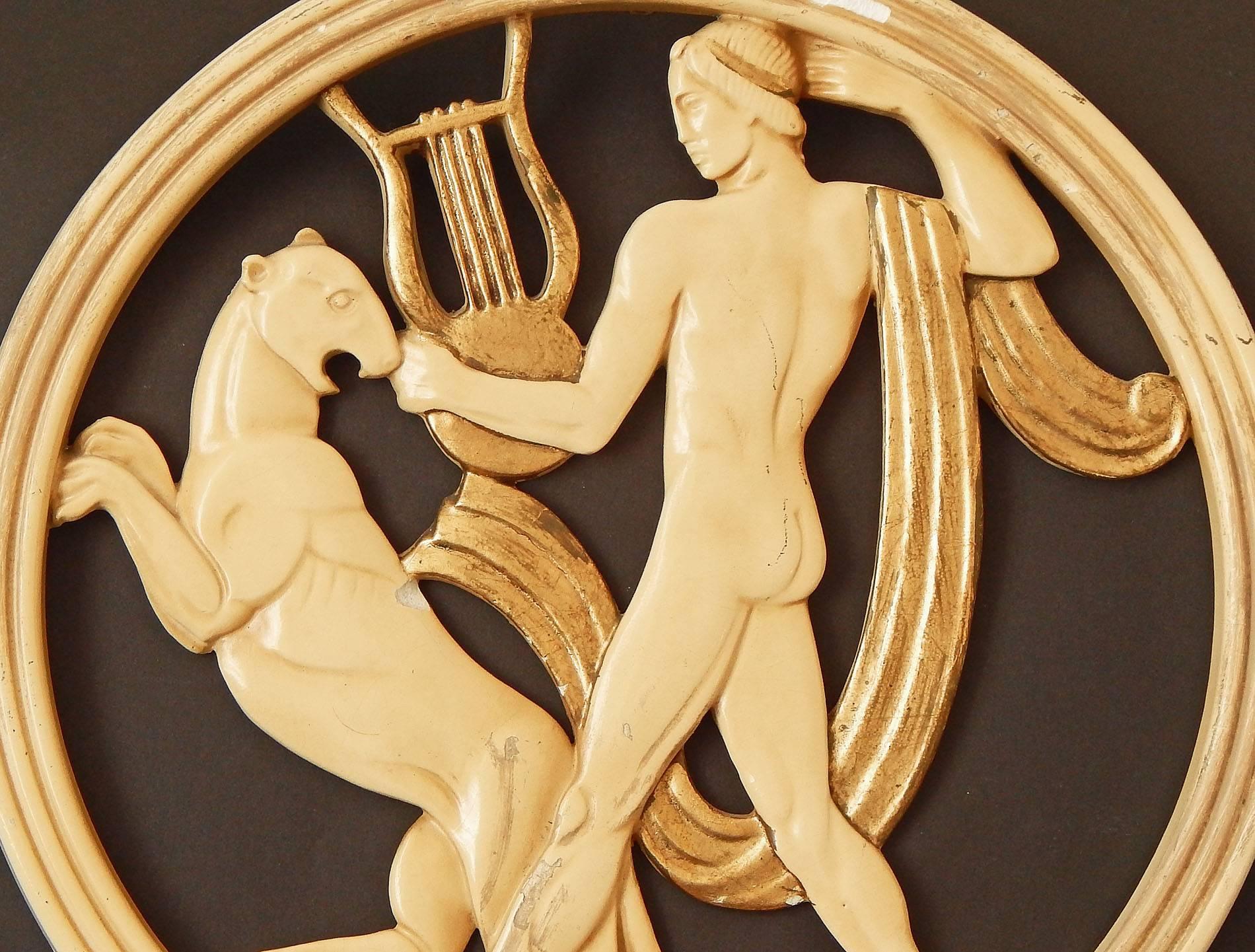 Silkily finished in tones of cream and gold, with very fine bas relief detail, this pair of mythological panels was produced by the New Art Wares company in the 1930s. One panel depicts a nude Orpheus with his lyre, accompanied by a rearing panther,