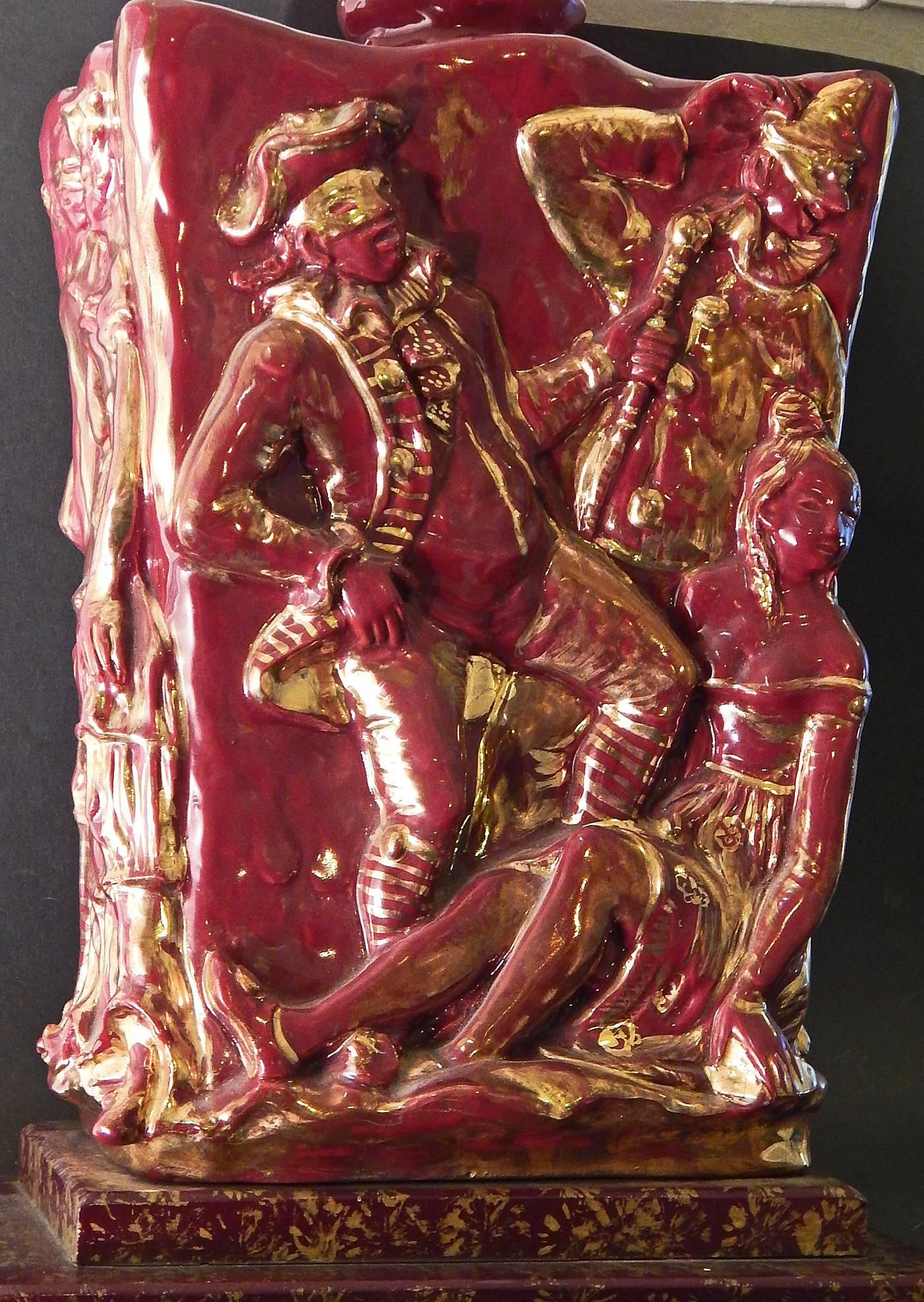 Dieses seltene Lampenpaar aus der Mitte des Jahrhunderts ist mit einer üppigen Glasur in der Farbe von Rotwein und leuchtendem Gold verziert und zeigt eine Gruppe von Karnevalisten in Masken und festlicher Kleidung. Das Paar ist von Eugenio