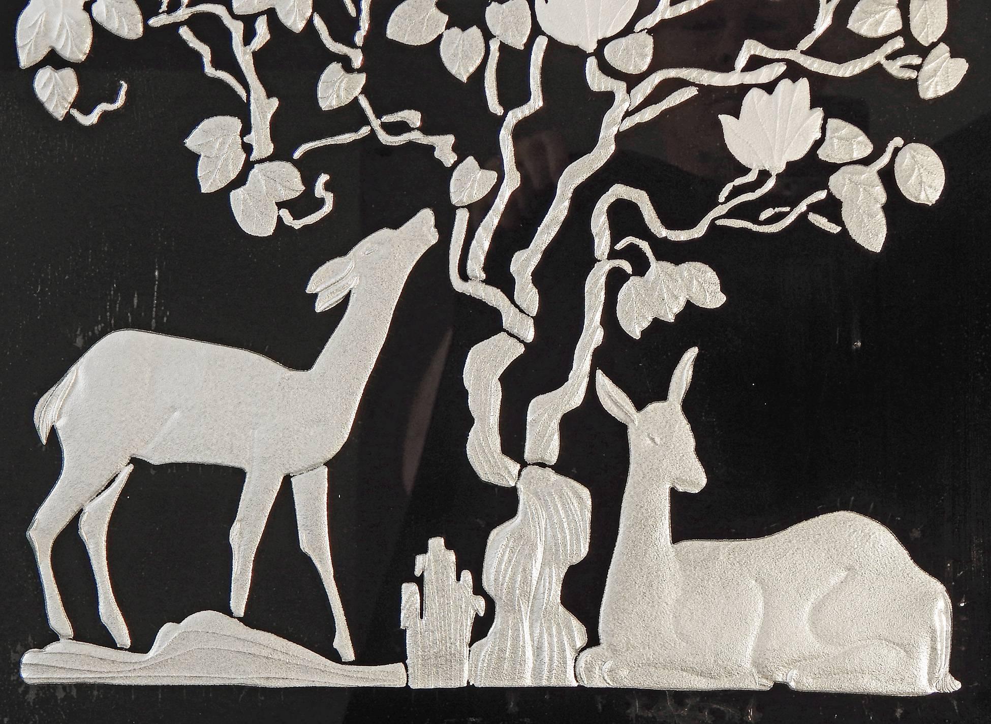 Stunning and very rare, this high style Art Deco mirror features a pair of deer under a spreading tree, all alive with a silvery shimmer that is entrancing. The background is reverse painted in black and the sculptural details are in molded glass,