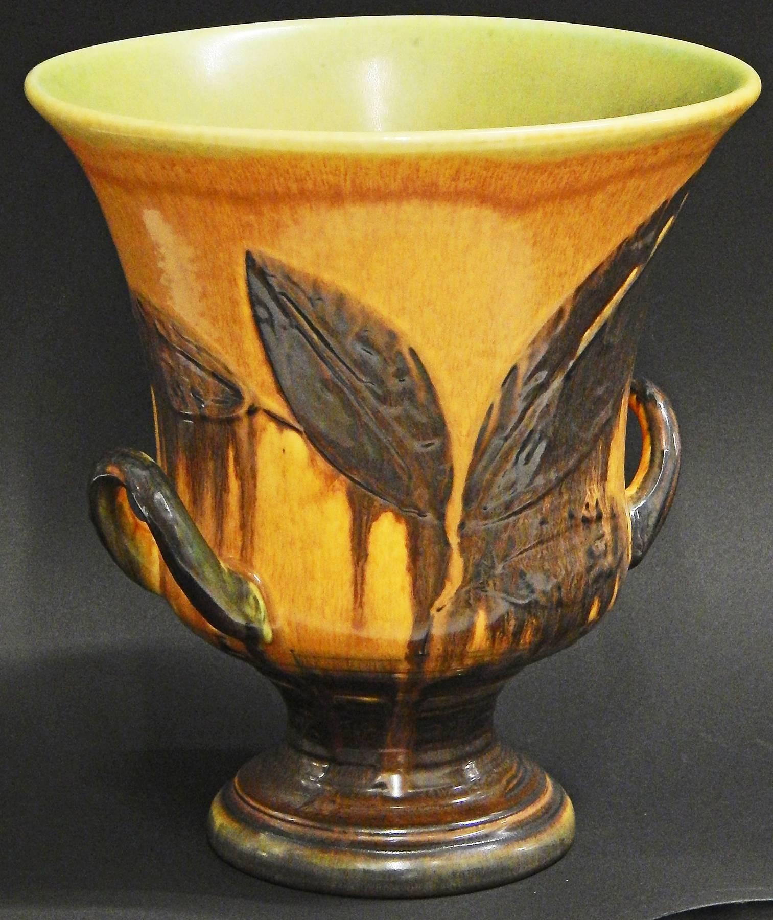 A marvelous and important example of William Hentschel's artistry at the famed Rookwood Pottery in Cincinnati, this large, two-handled urn depicts stylized leaf forms in a dark brown glaze on a ground of rusty-orange. Hentschel is famous for his